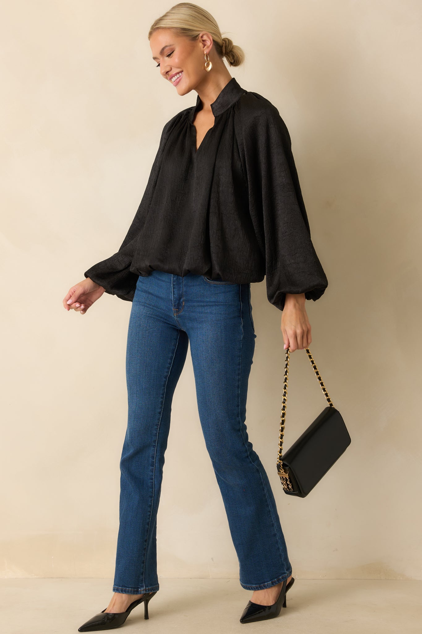 Sleek black satin top with long sleeves, gathered cuffs, and a gently ruched neckline for subtle shaping.