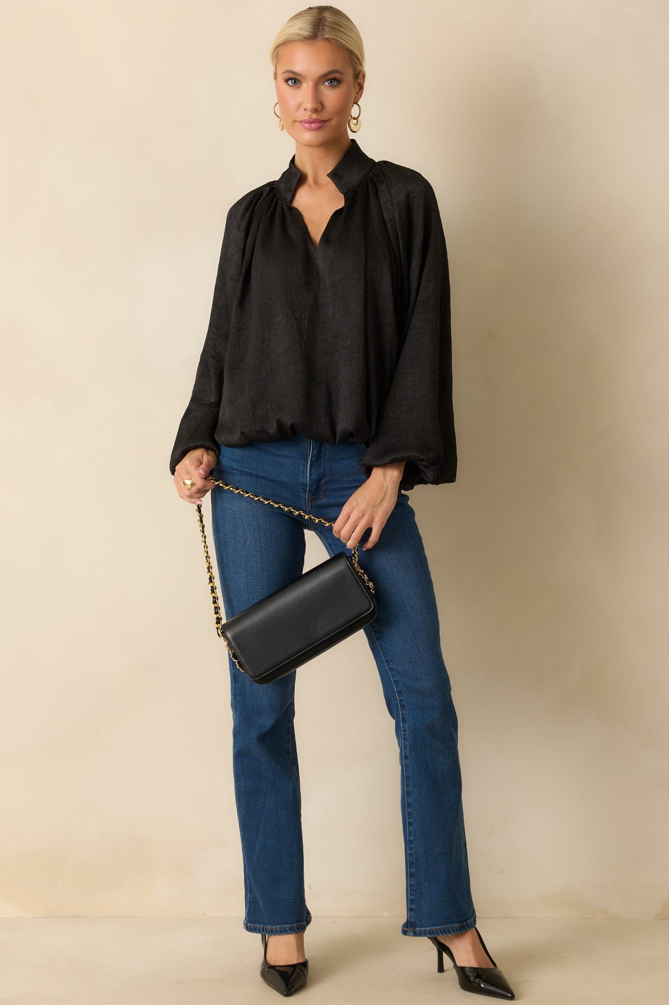Relaxed-fit black satin V-neck top with subtle texture and billowy peasant sleeves.