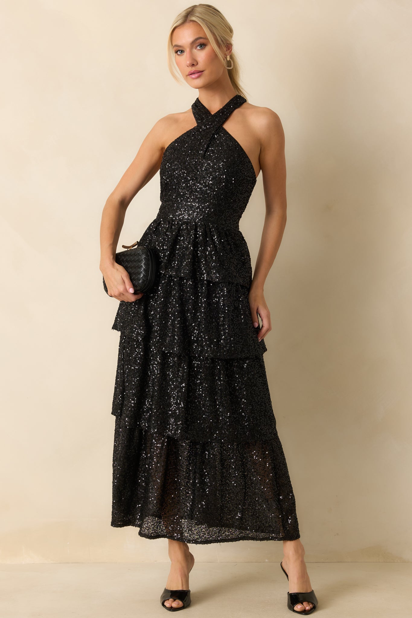 Fitted black sequin dress with a high halter neckline and layered skirt creating elegant movement.