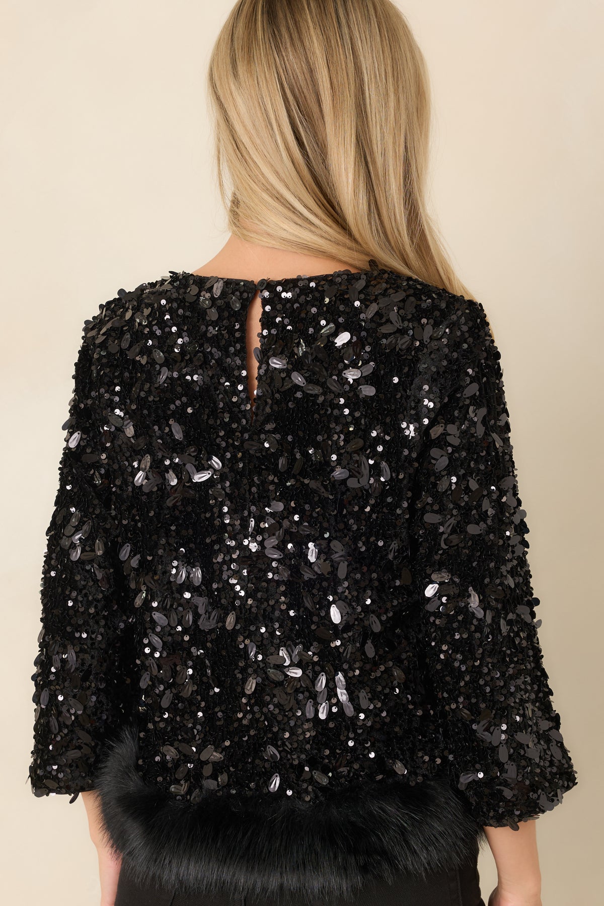 Back of the black sequin top featuring a keyhole opening with a single-button closure.
