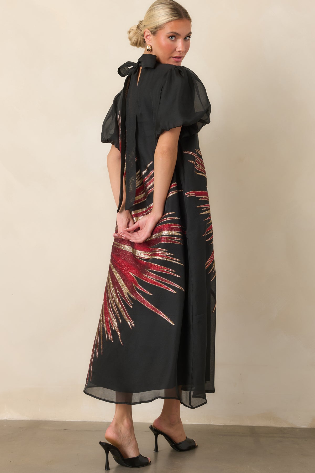 Rear view of the sheer black midi dress featuring a high neckline and keyhole opening with long statement ties.