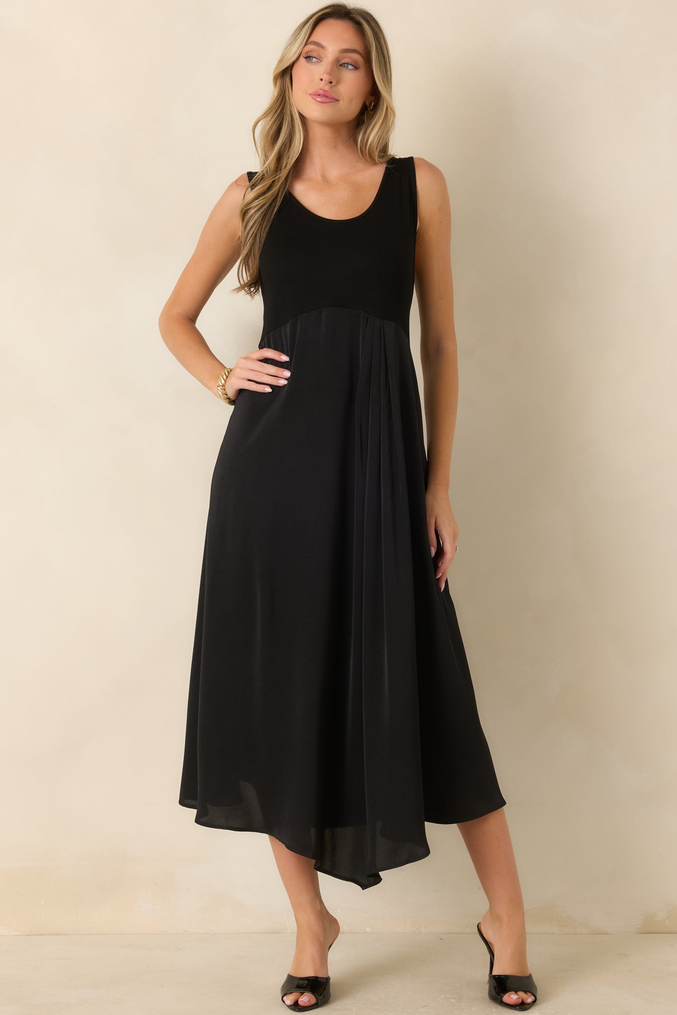 Black sleeveless midi dress featuring a stretch-knit bodice, scoop neckline, and a flowing satin skirt with an elegant drape.