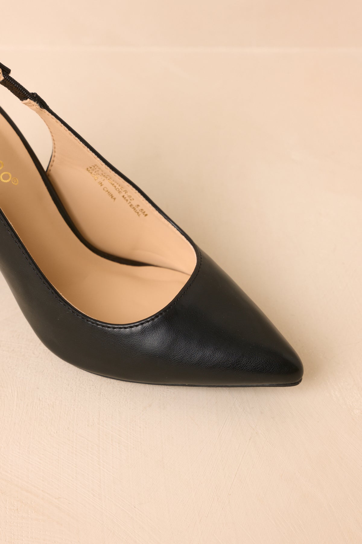 Sleek black slingbacks feature a pointed toe, open design, and elasticized strap above the tall block heel.