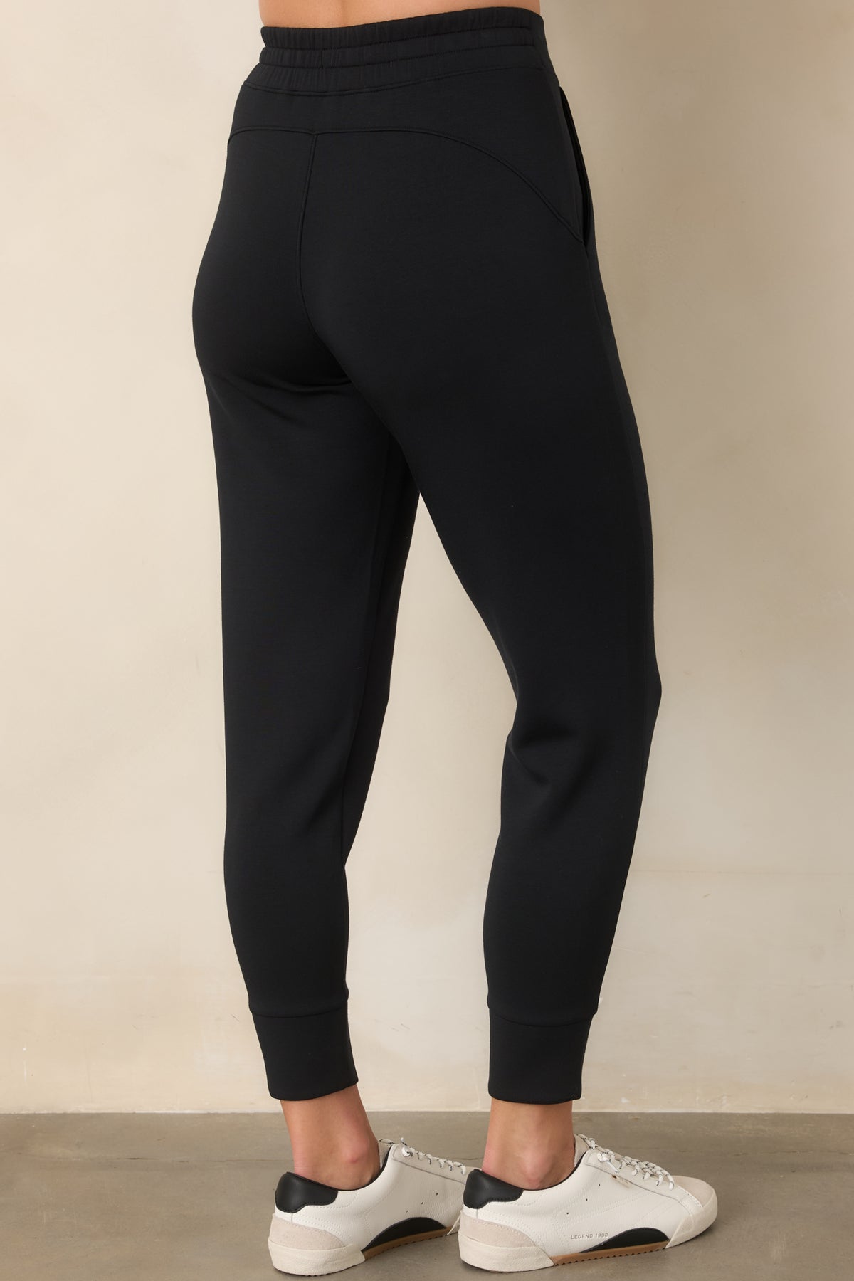 Rear view of the black spacer joggers showing their relaxed fit, tapered legs, and slim banded cuffs.