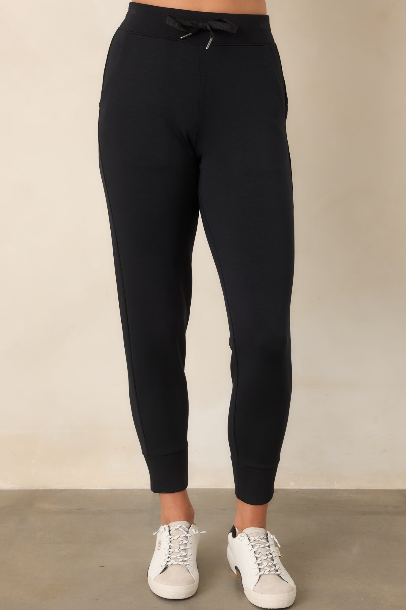 Black spacer joggers showing their smooth fabric, tapered leg shape, and clean banded cuff.
