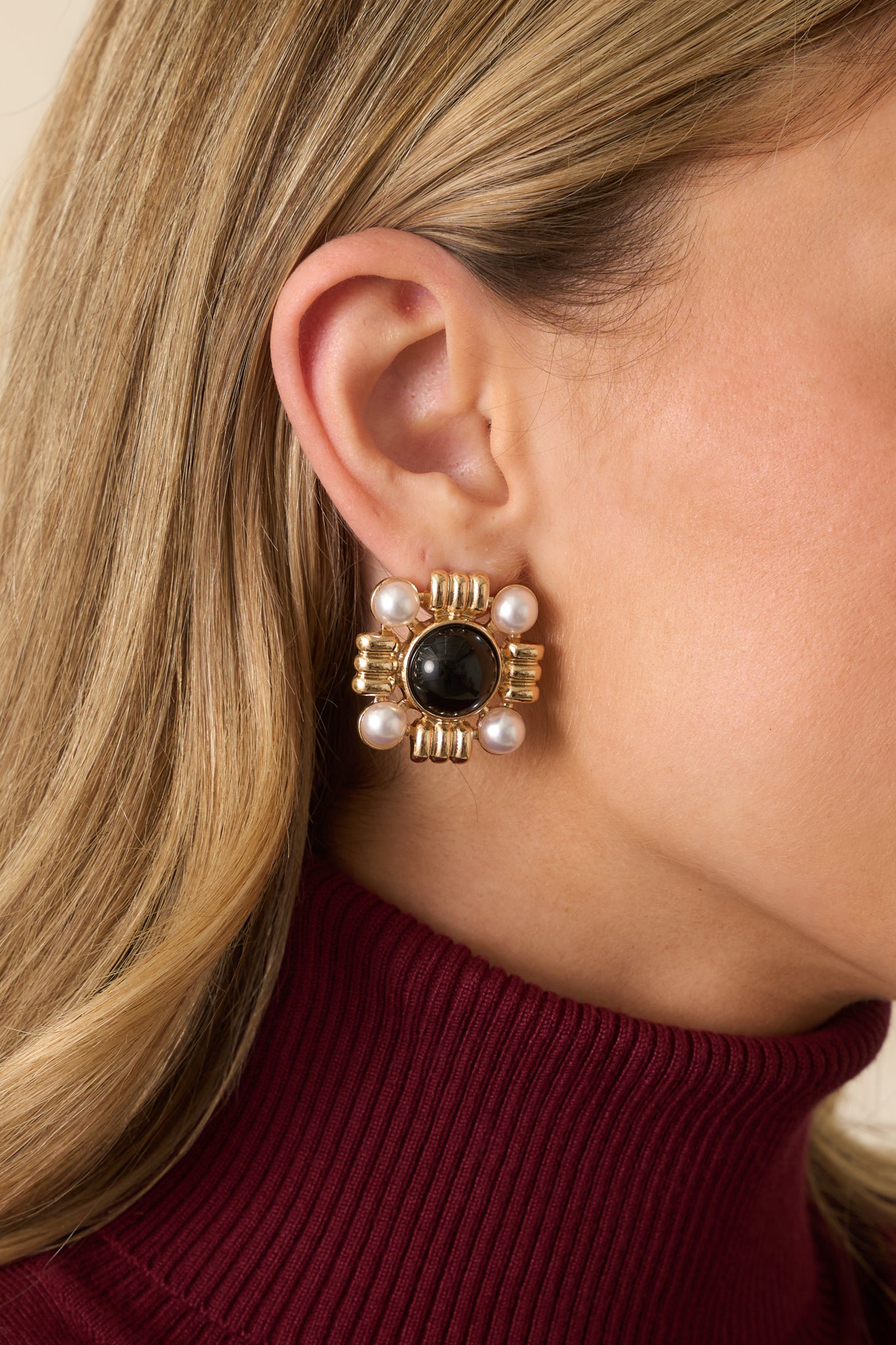 Black stone square earrings with ivory pearls in each corner and intricate gold textures.