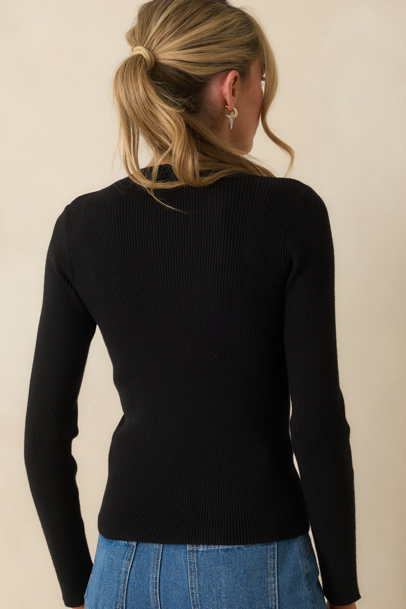 Rear view of the black sweater with a fitted silhouette and long sleeves.