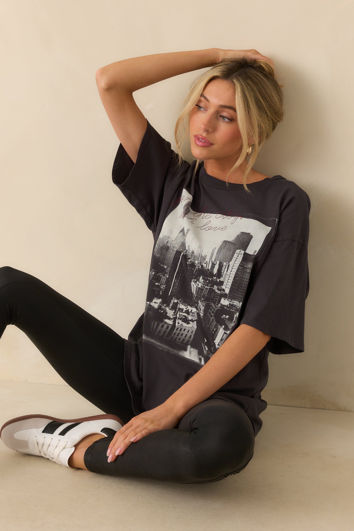 Black tee with city skyline graphic and red embroidered script across the front.