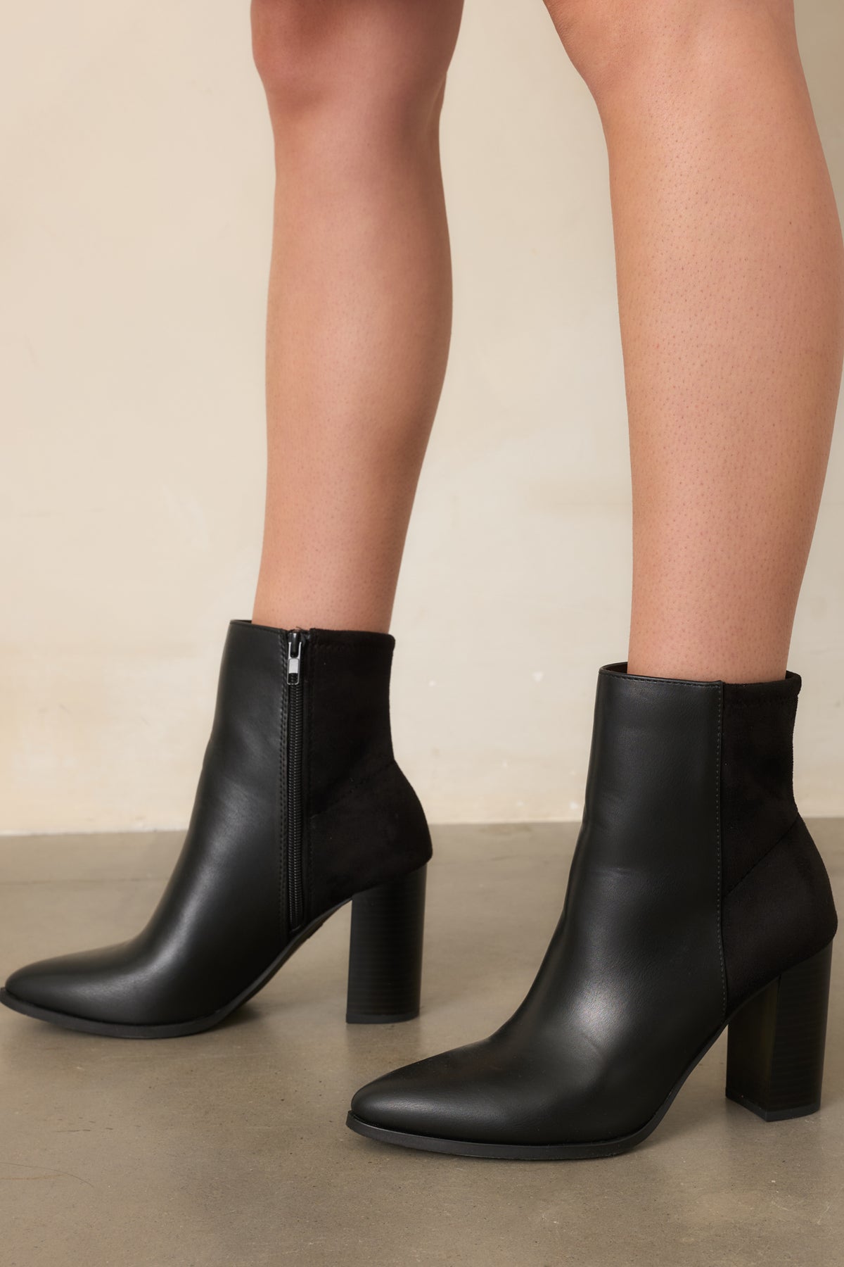 Detailed view of the tonal faux suede back panel and structured ankle shaft on the black boots.