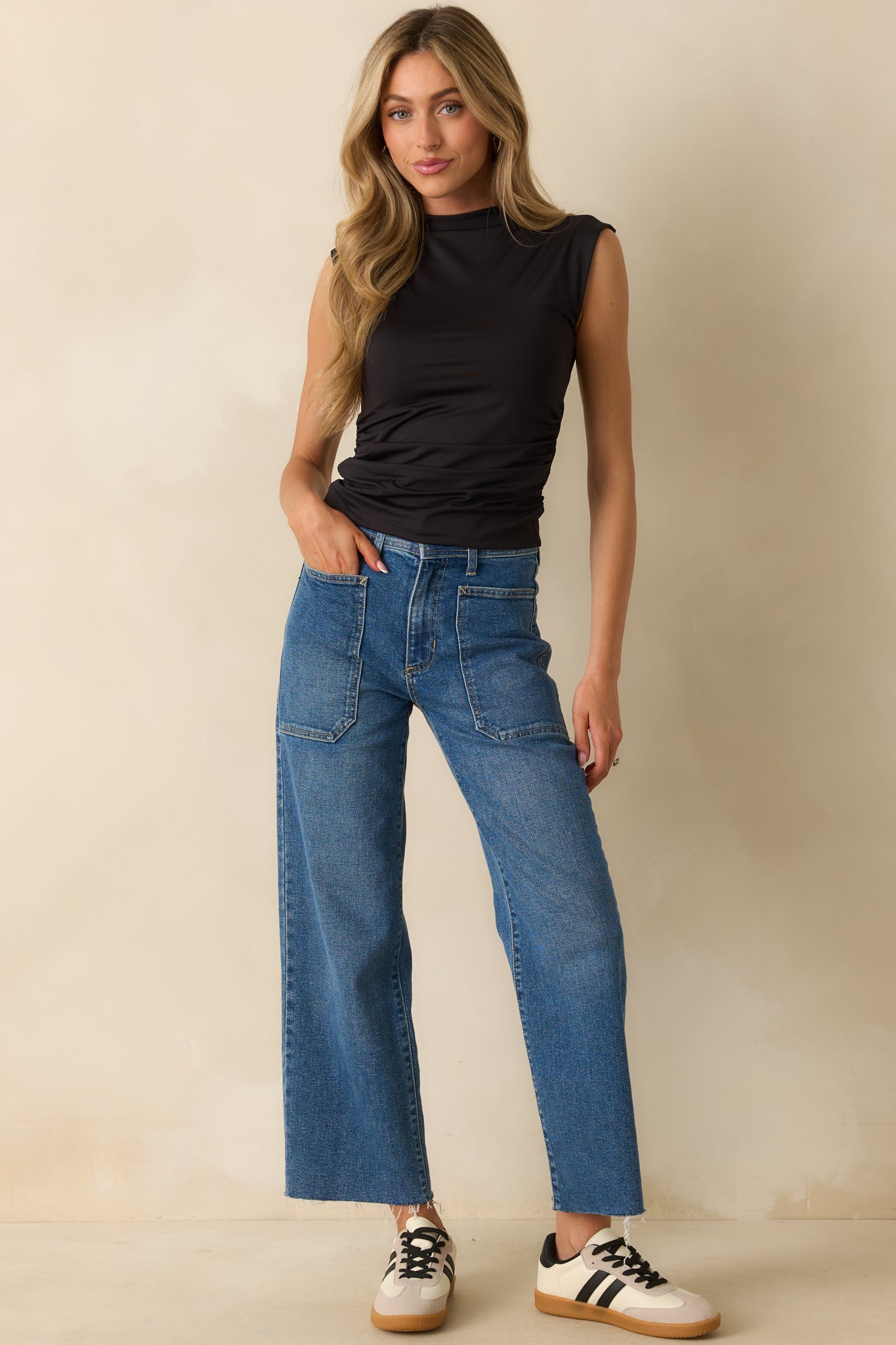 Front view of a fitted black top featuring a mock neck and ruched sides.