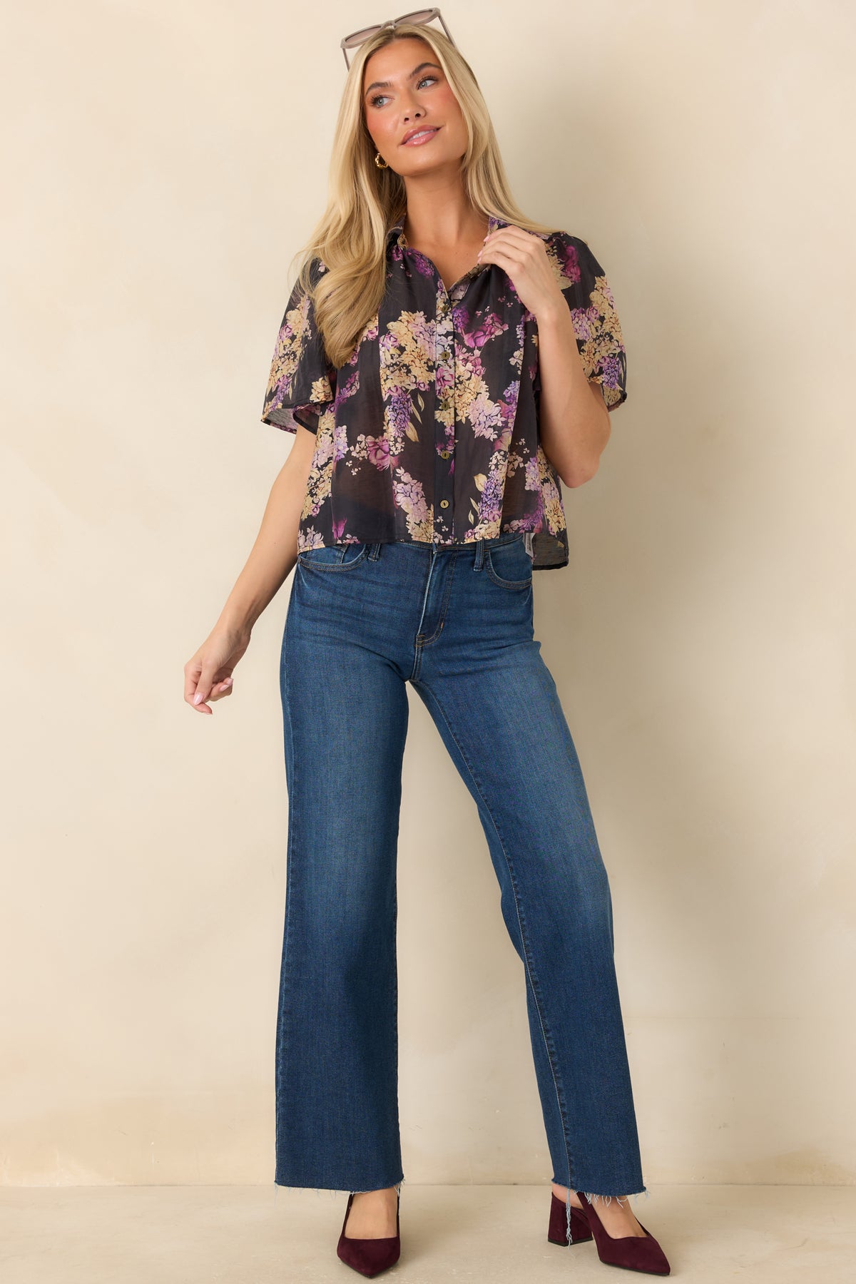 Black top with scattered pink and lilac flowers, creamy yellow accents, and a relaxed silhouette with flutter sleeves.