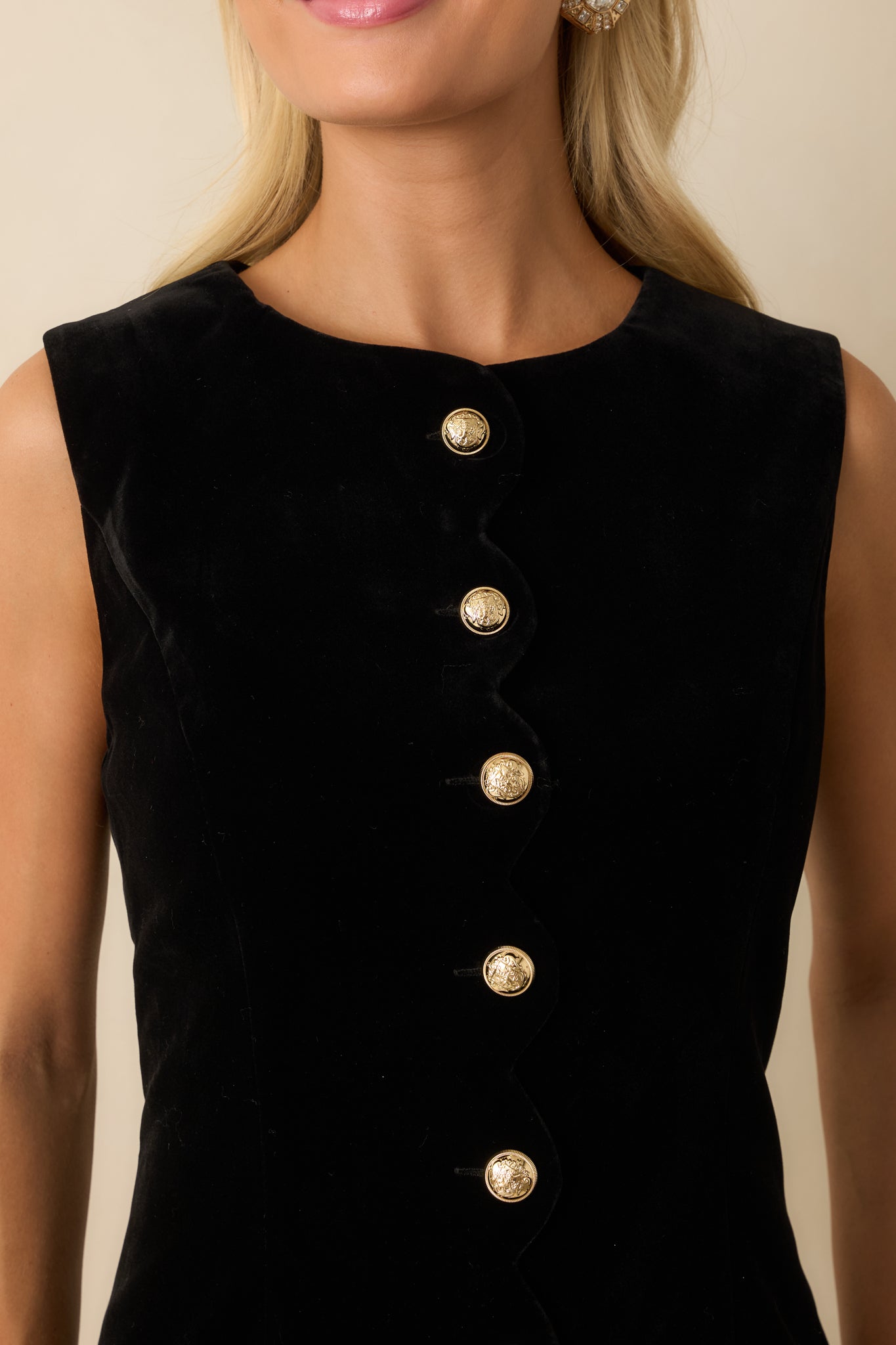 Close-up of the black velvet fabric showing the scalloped placket and shimmering gold statement buttons.