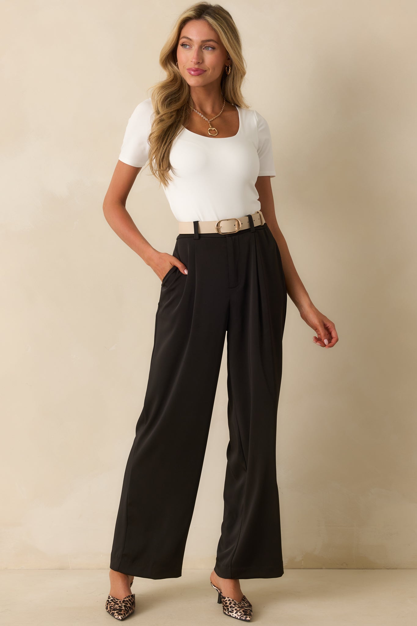 Black wide-leg trousers with a high-rise waist, front pleats, and a flowing silhouette that elongates the leg line.