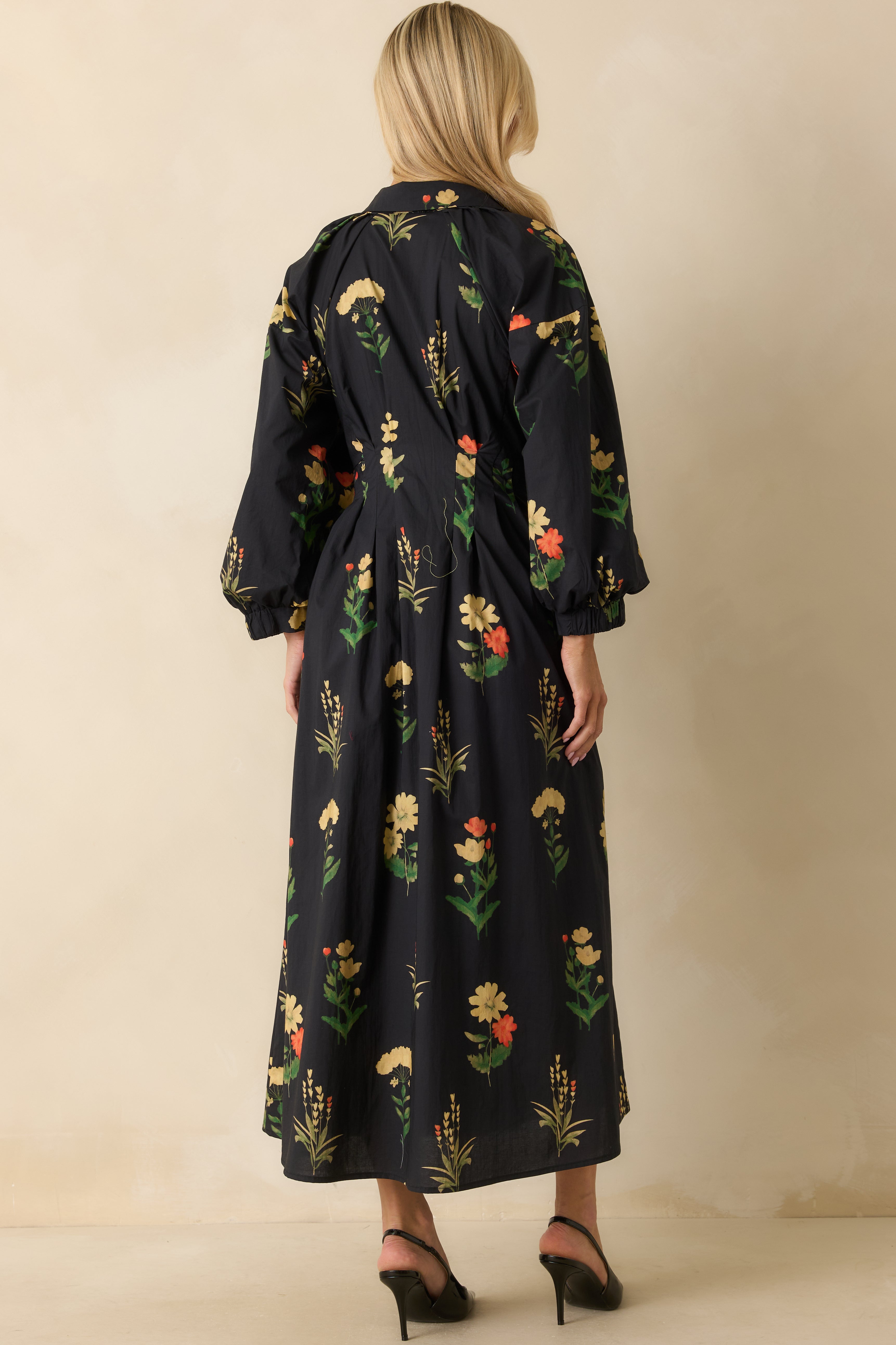 Rear view of the black woven dress showing bishop sleeves, pleated waist, and allover floral pattern.