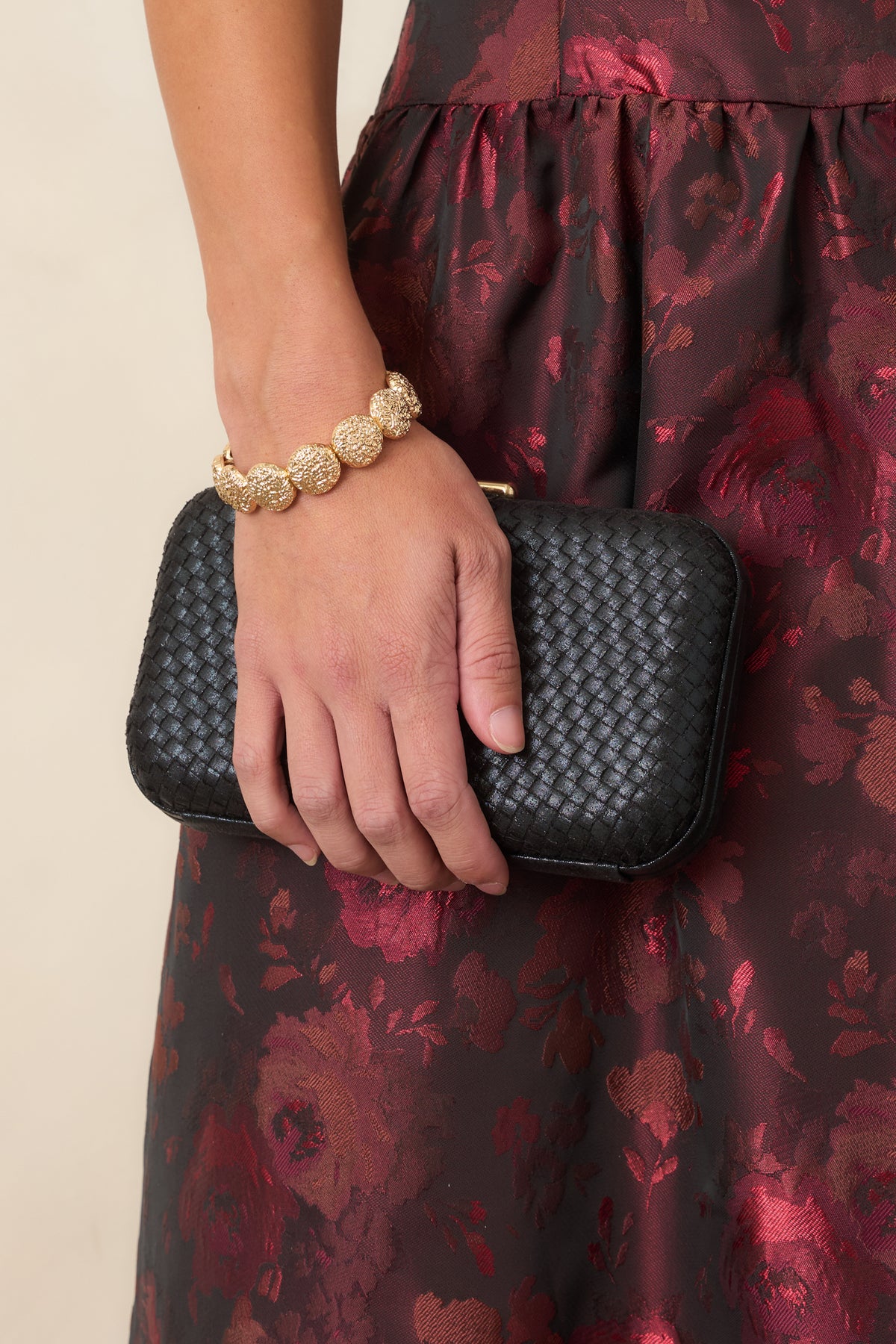 Black woven clutch with a structured rectangular shape, hard case body, rounded edges, and top clasp closure.
