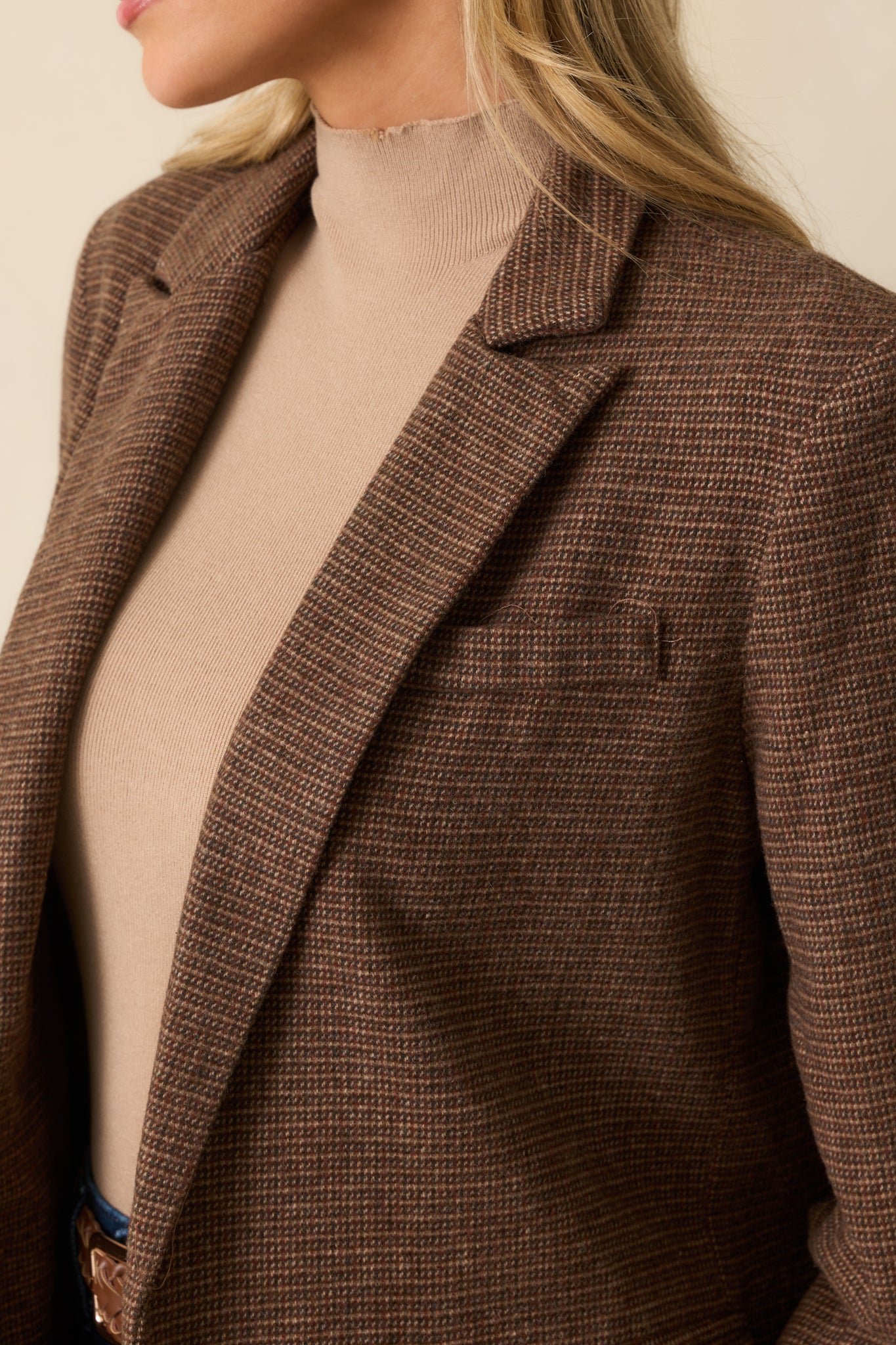 Close-up of the blazer’s notched lapel and button cuff, showcasing textured woven fabric.