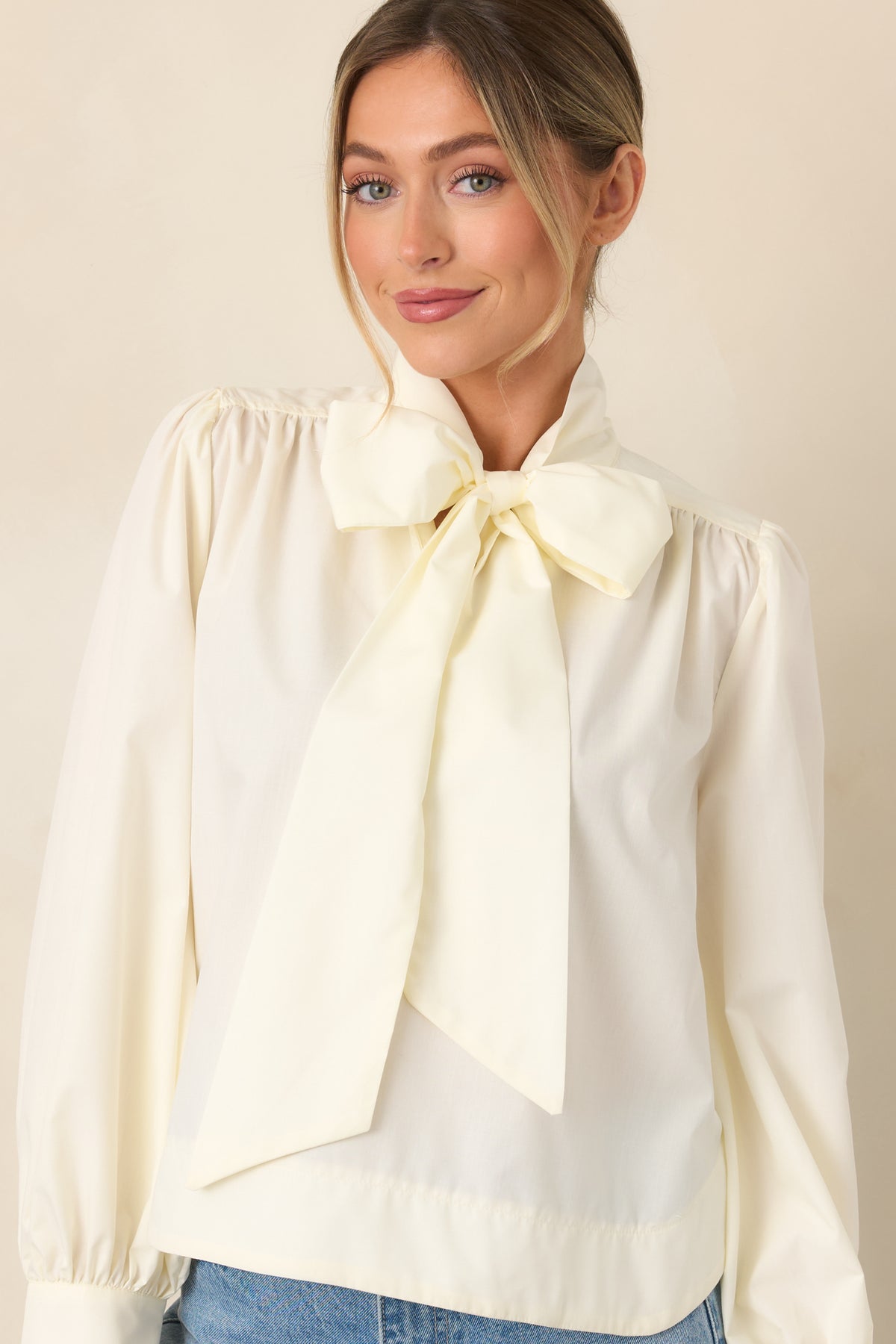 Detailed view of the statement tie neckline and smooth polyester-cotton blend fabric across the blouse front.