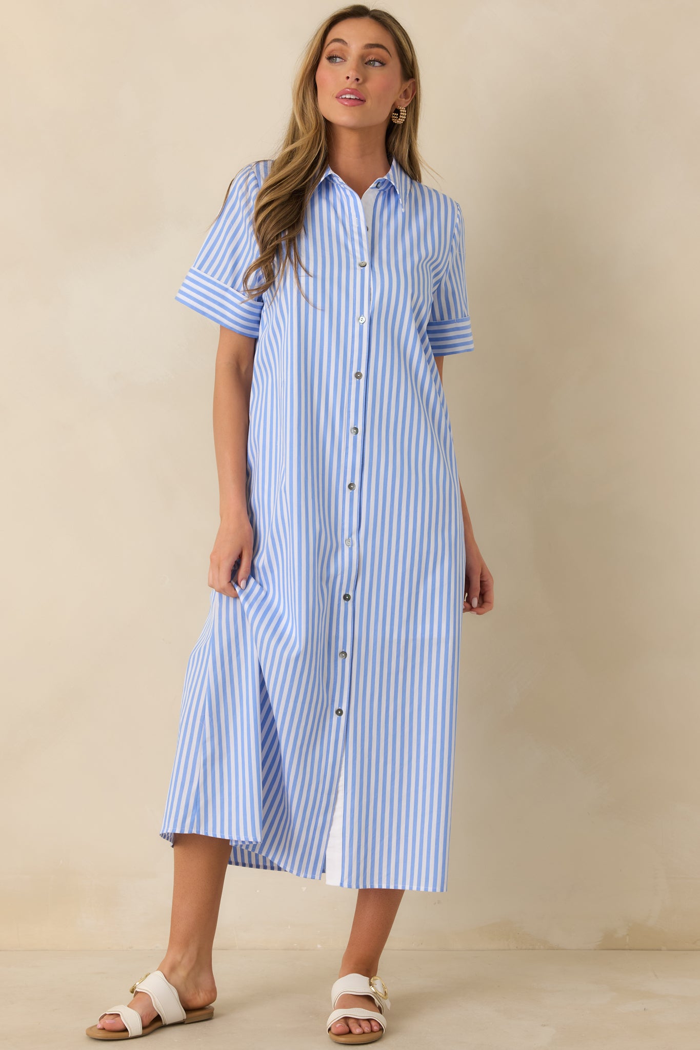 Front view of a blue and white striped shirt dress with a collared neckline, short cuffed sleeves, and full button-front closure.