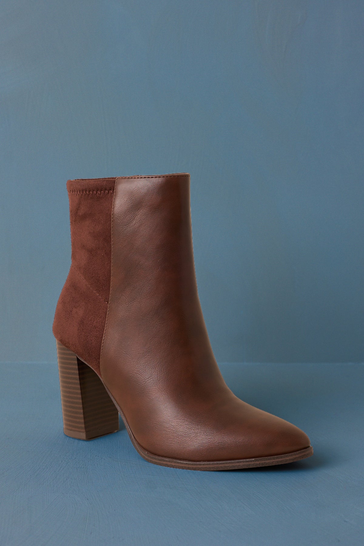 Angled view of the boots showcasing the inner side zipper closure and streamlined profile on blue back drop.