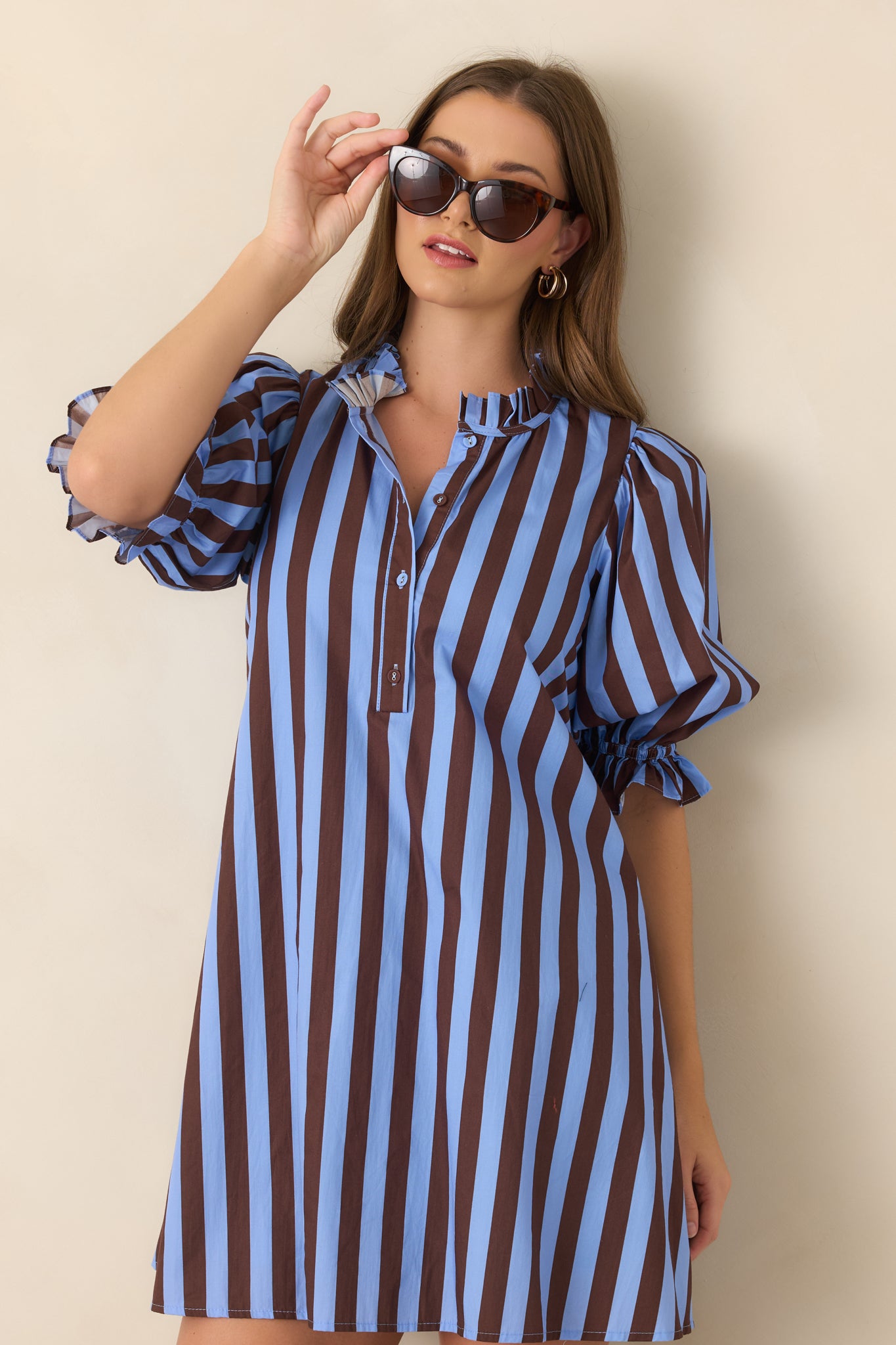 Soft blue and brown striped mini dress highlighting the ruffled mock collar, partial button-front placket, and gathered three-quarter puff sleeves.