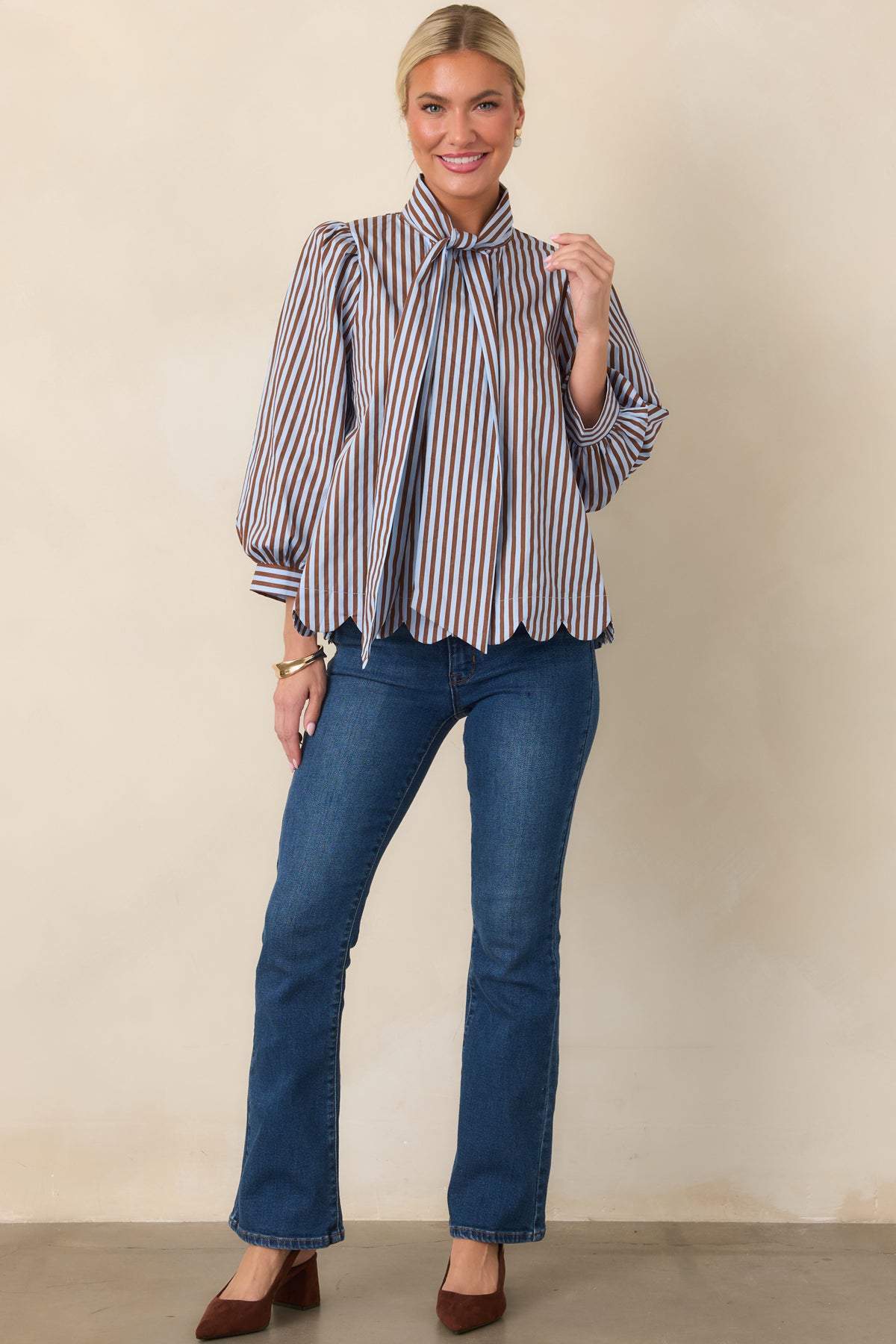 Light blue and brown striped blouse showcasing softly gathered shoulders, three-quarter sleeves, and a button-front design.