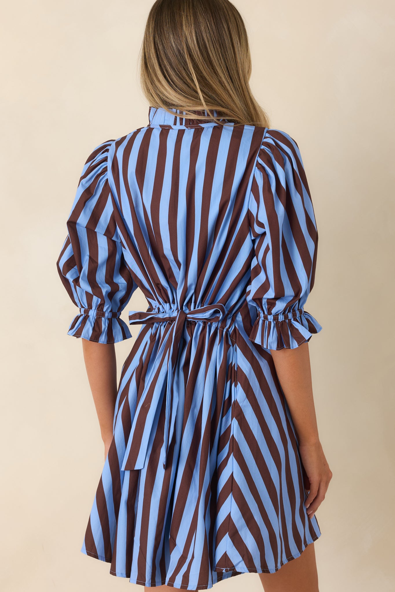 Back view of the striped cotton mini dress featuring a relaxed shift silhouette, puff sleeves, and adjustable tie-back waist.