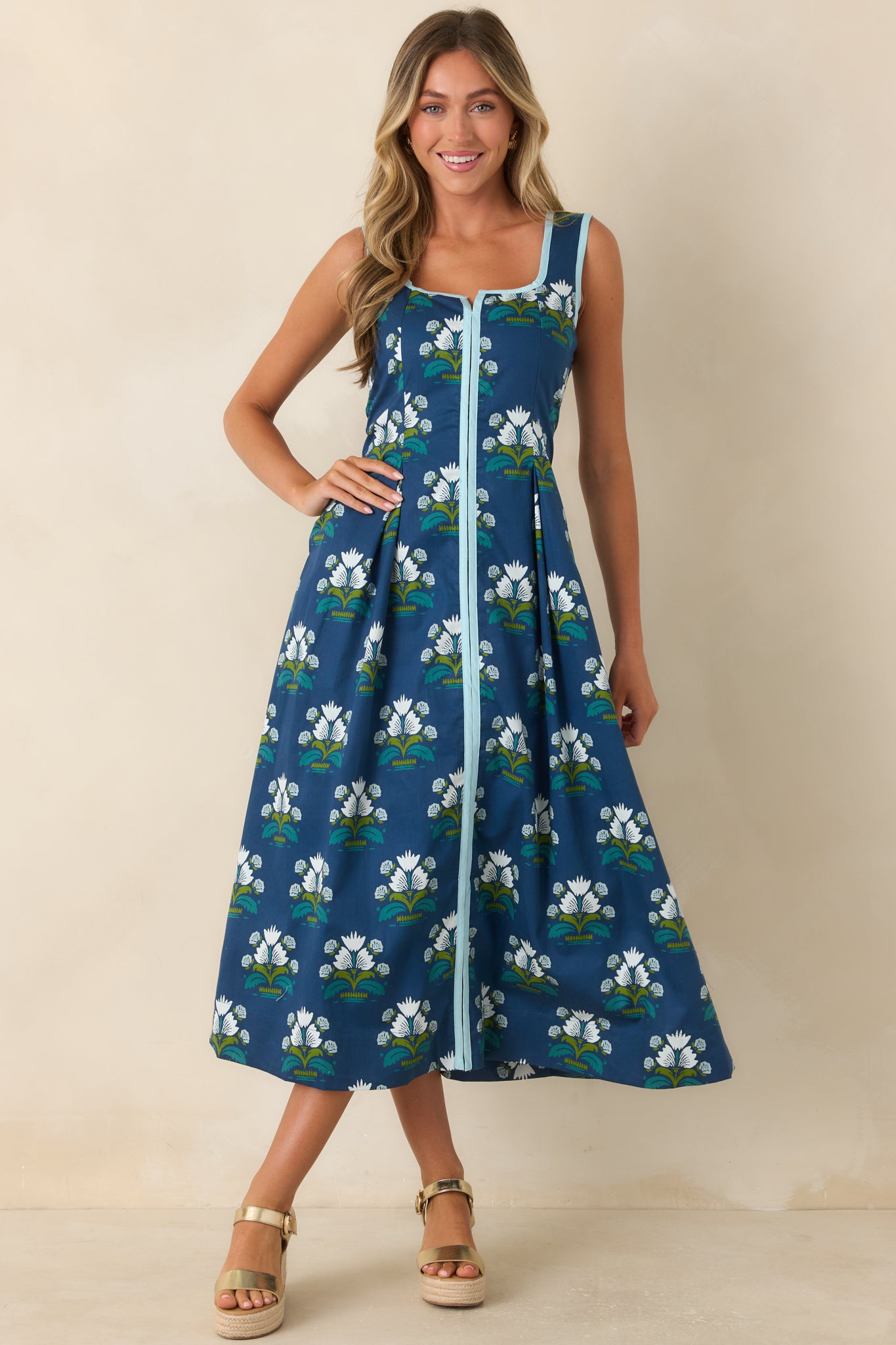 Blue cotton dress featuring a white, teal, and green floral motif, square neckline, and pleated A-line skirt.