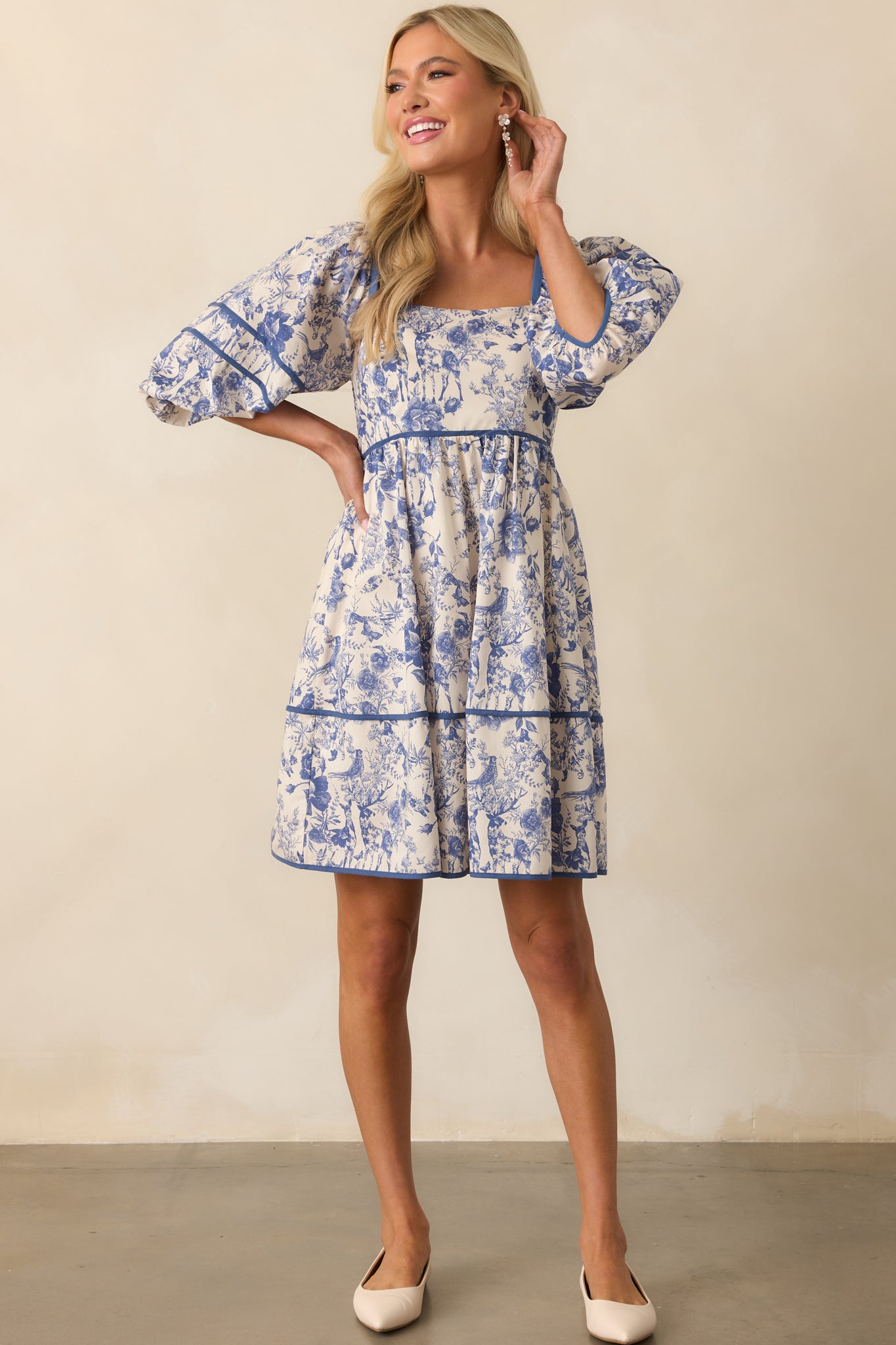 Front-facing full body image of the blue dress, highlighting the structured puff sleeves and feminine silhouette created by the tiered skirt.