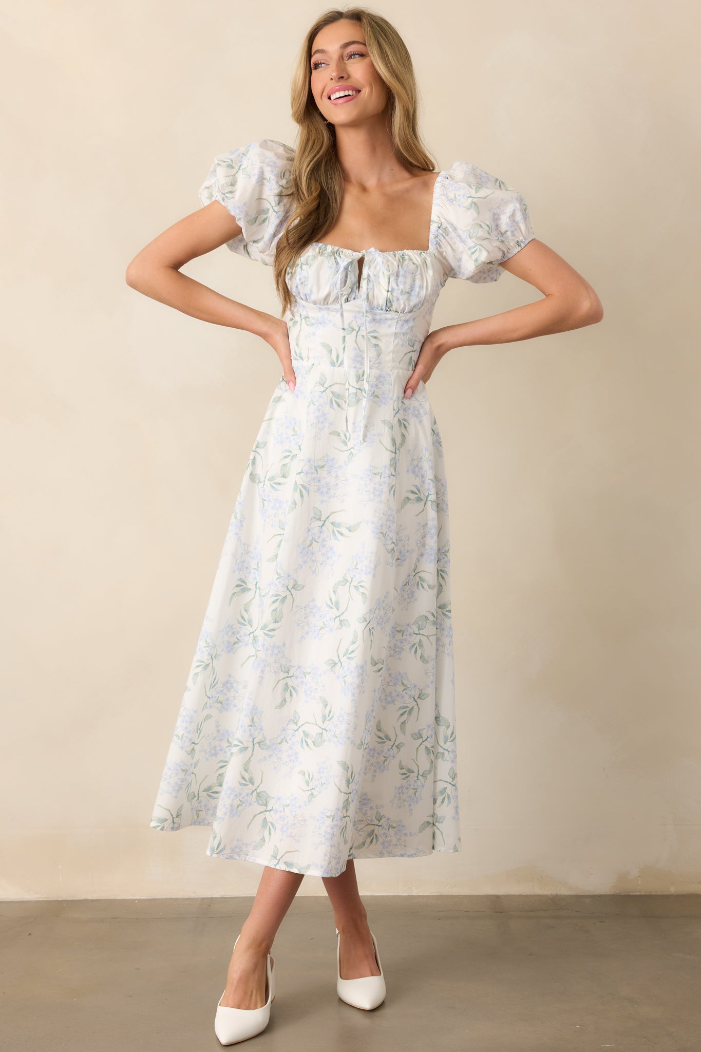 A front-facing view of the light blue floral print maxi dress, with an elastic sweetheart neckline, bustier-style stitching along the bodice, and puff sleeves with elastic cuffs. The hidden back zipper is subtly incorporated