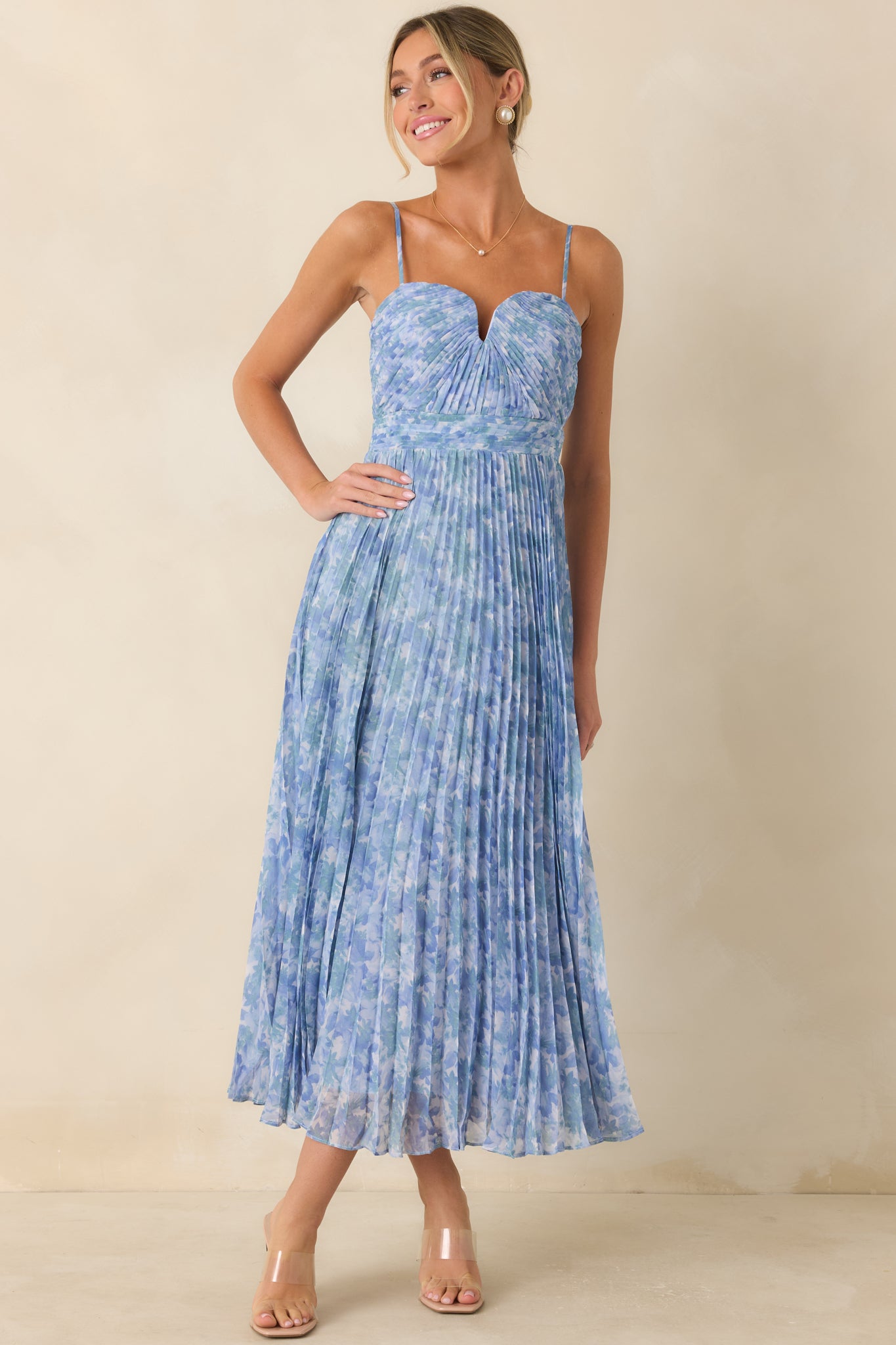 Flowing blue floral dress featuring a subtle V-bar neckline detail and airy pleated movement throughout.