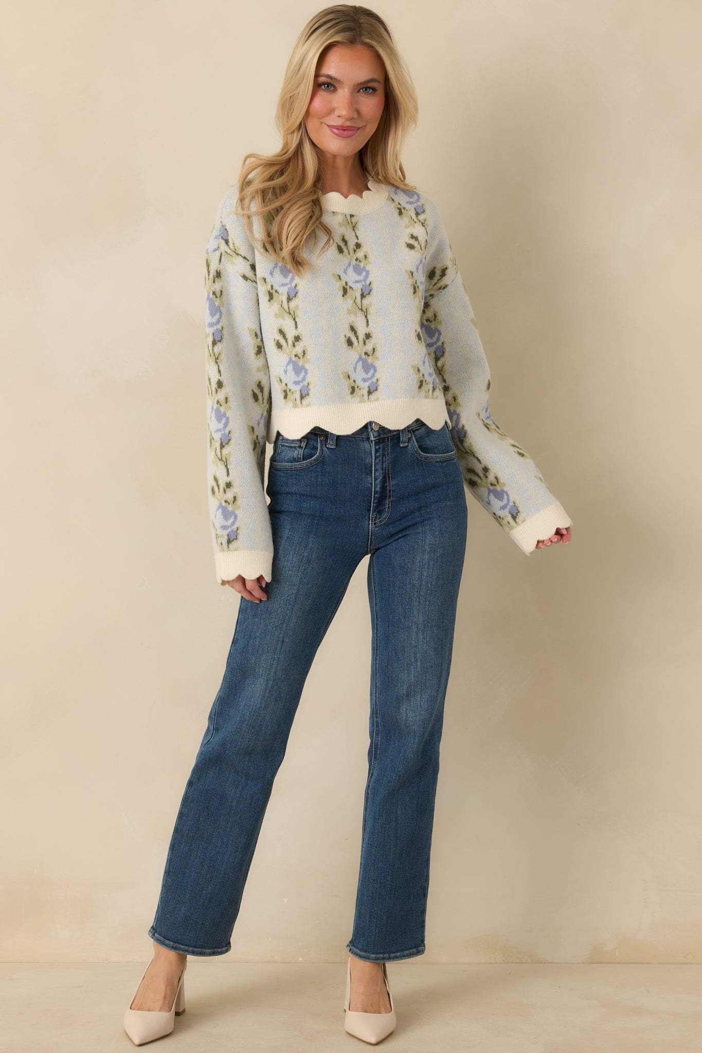 Blue floral knit sweater with a relaxed, slightly cropped silhouette and scalloped hem detailing.