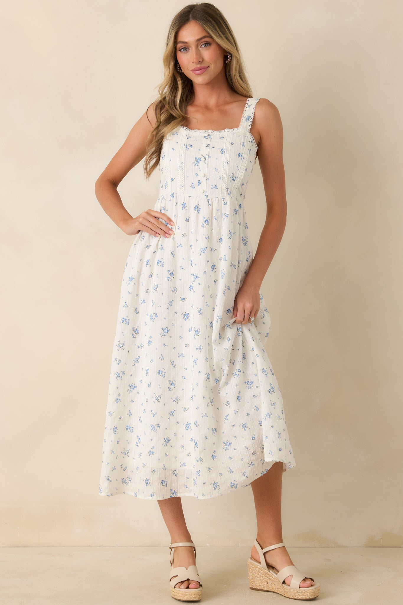 Blue floral midi dress showcasing delicate lace accents, a button front closure, lightweight cotton texture, and a softly flowing lined skirt.