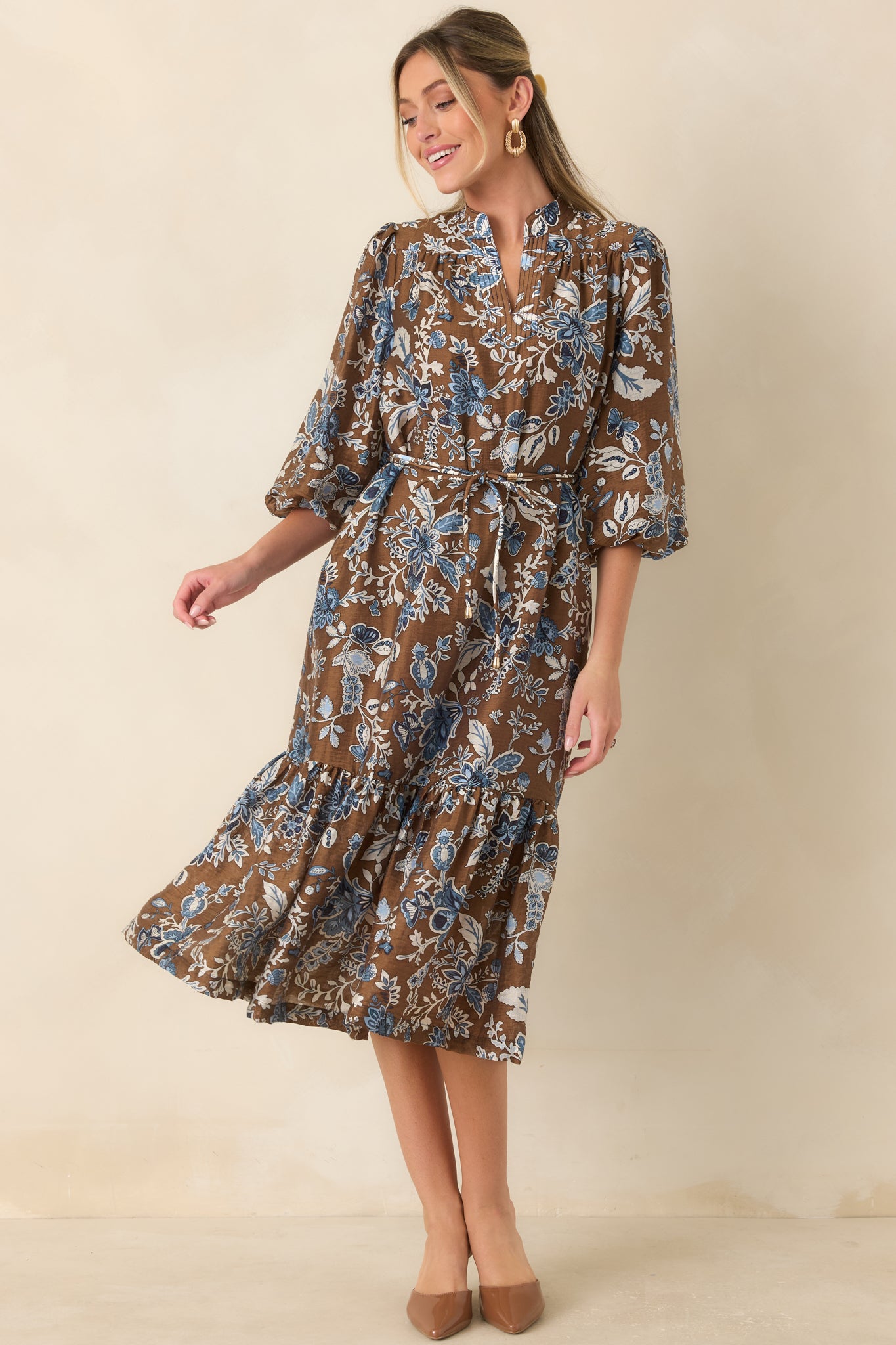 Blue floral midi dress showcasing a pintuck neckline, three-quarter balloon sleeves, removable waist tie, and flowing skirt.