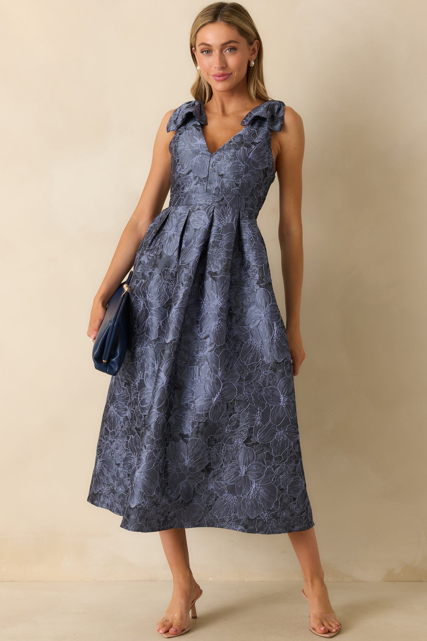 Blue floral midi dress with self-tie bow straps, v-neckline, sleeveless design, and relaxed fit.