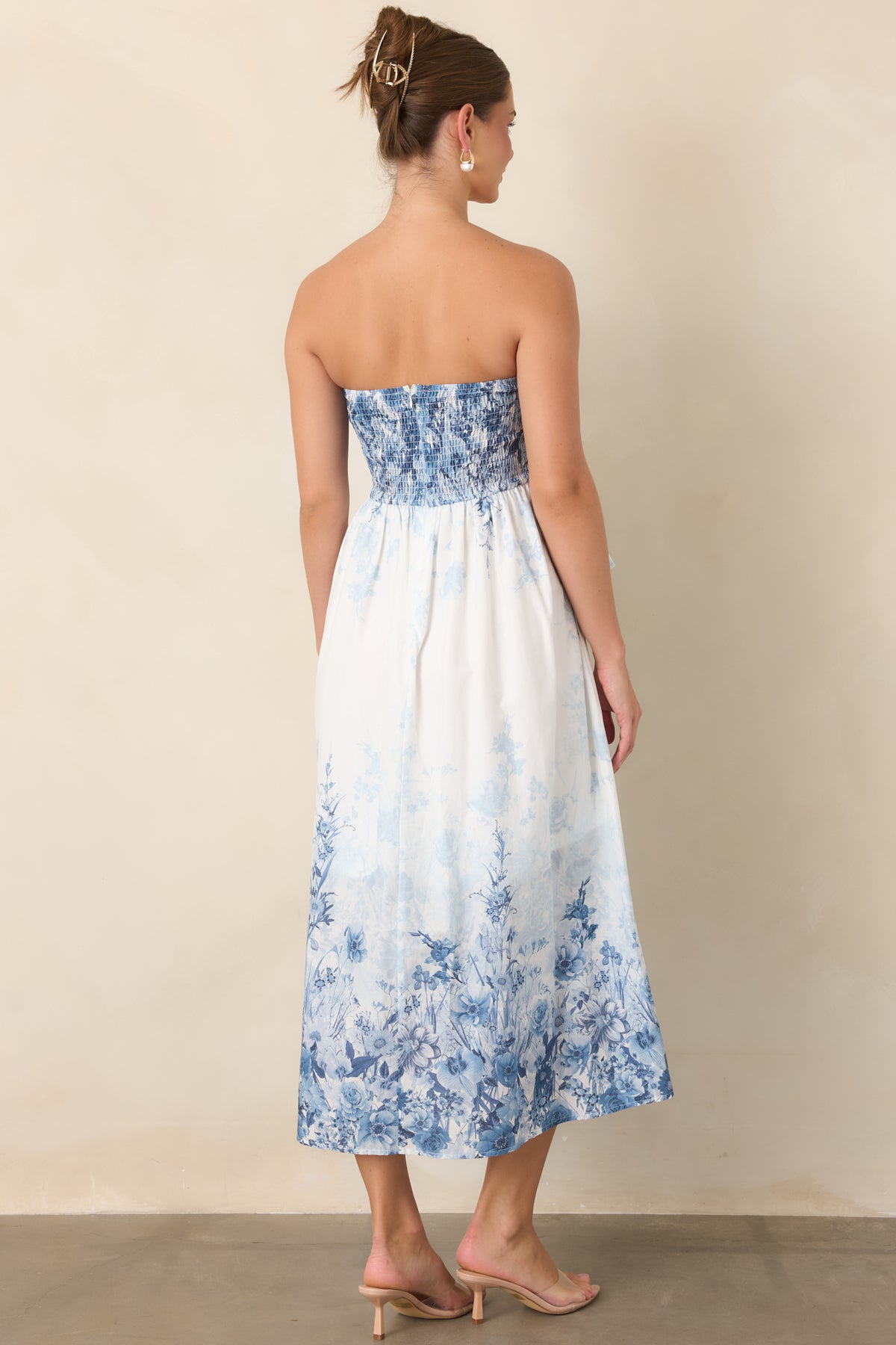 Rear of the blue floral midi dress showing the smocked back panel and concealed zipper.