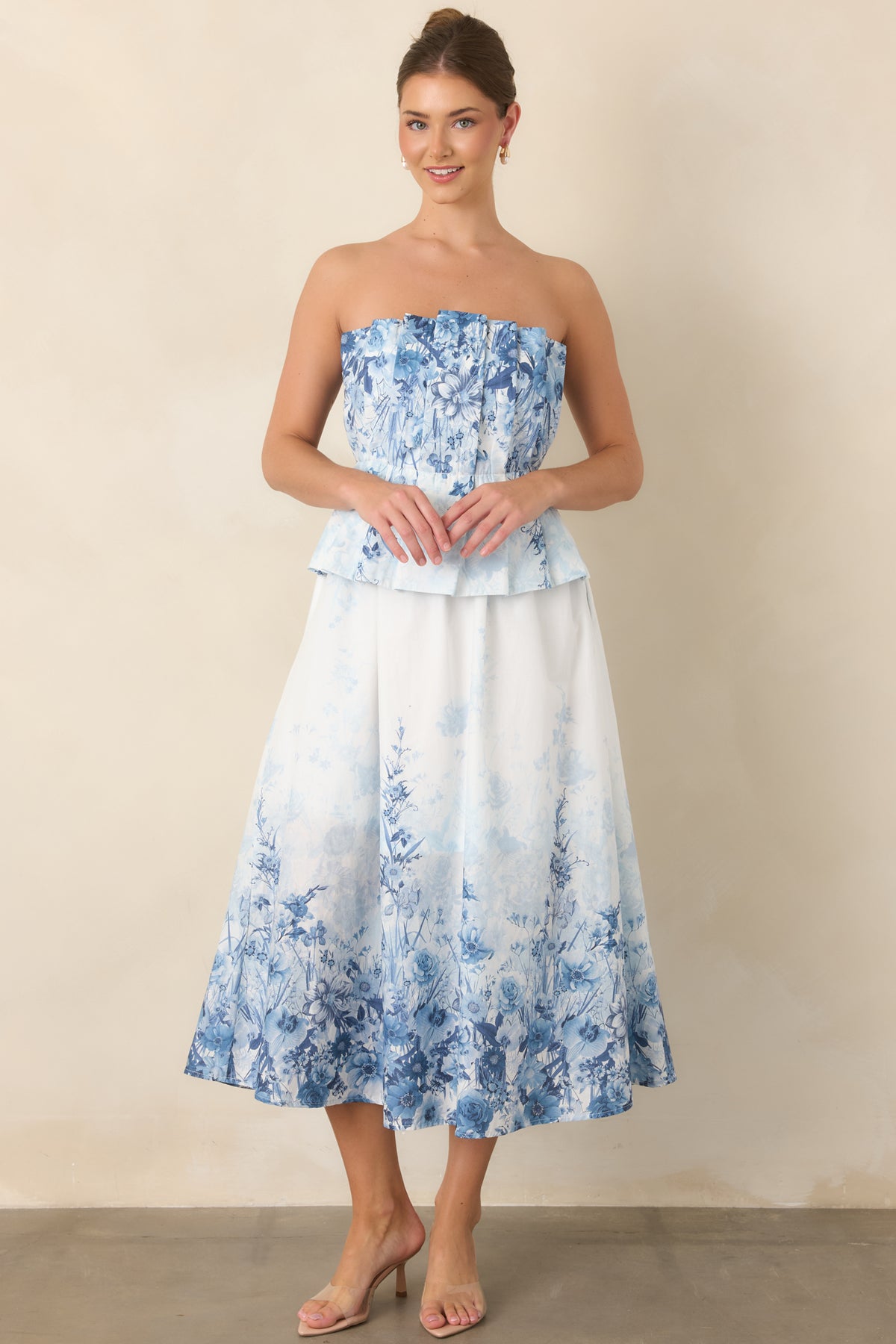 Blue floral midi dress with a strapless pleated bodice, defined waistband, and pockets.