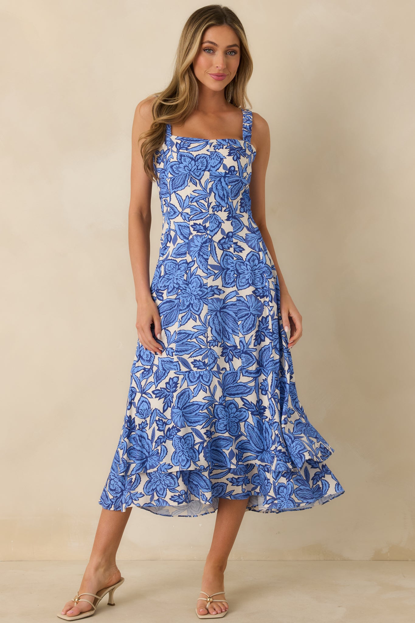 Blue floral midi dress with a square neckline, wide shoulder straps, and fitted paneled bodice.