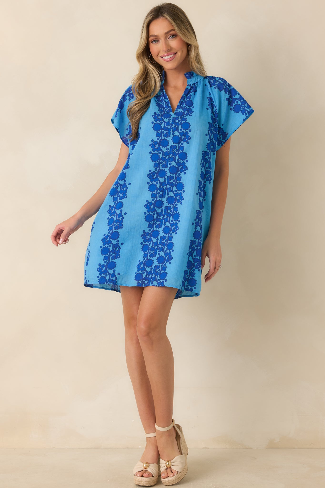 Blue cotton mini dress featuring a dark blue floral print, split neckline, and relaxed shift silhouette.