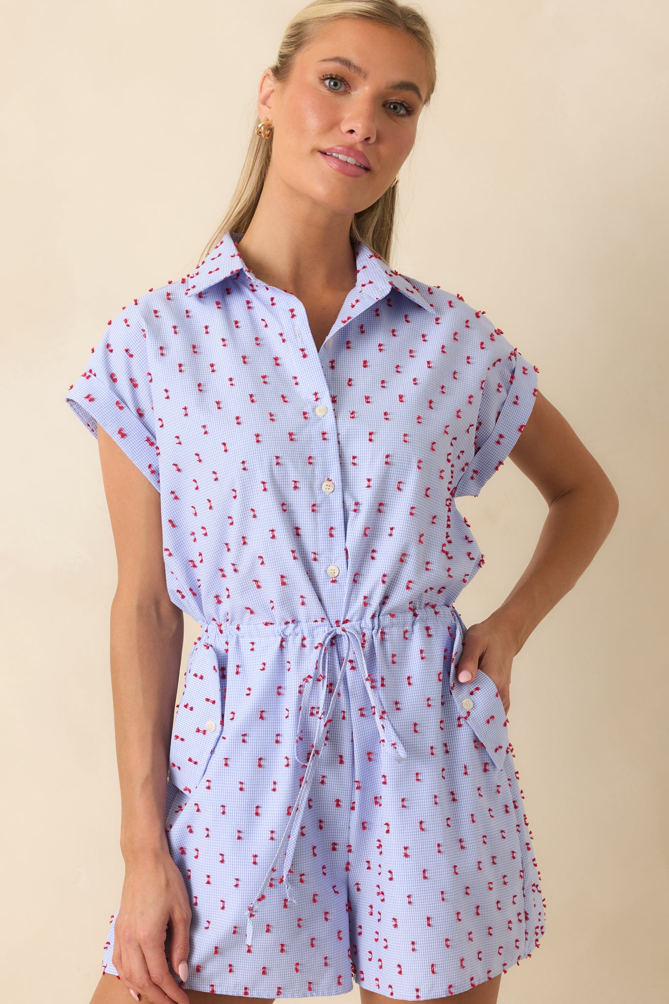 Blue gingham cotton romper showcasing the button-front design, relaxed fit, and charming embroidered accents.