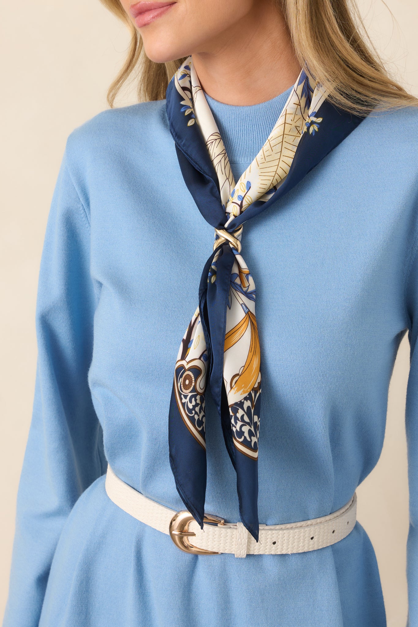Scarf featuring layered blue leaves, delicate branches, warm golden floral accents, and ornate corner details framed by a deep navy border.