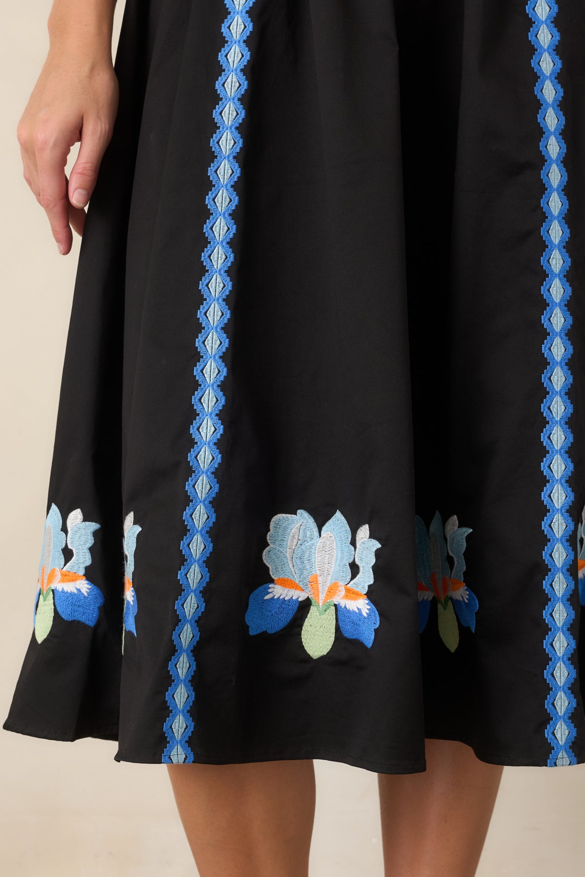Close-up of blue iris embroidery in cobalt, pale blue, mint, ivory, and orange.