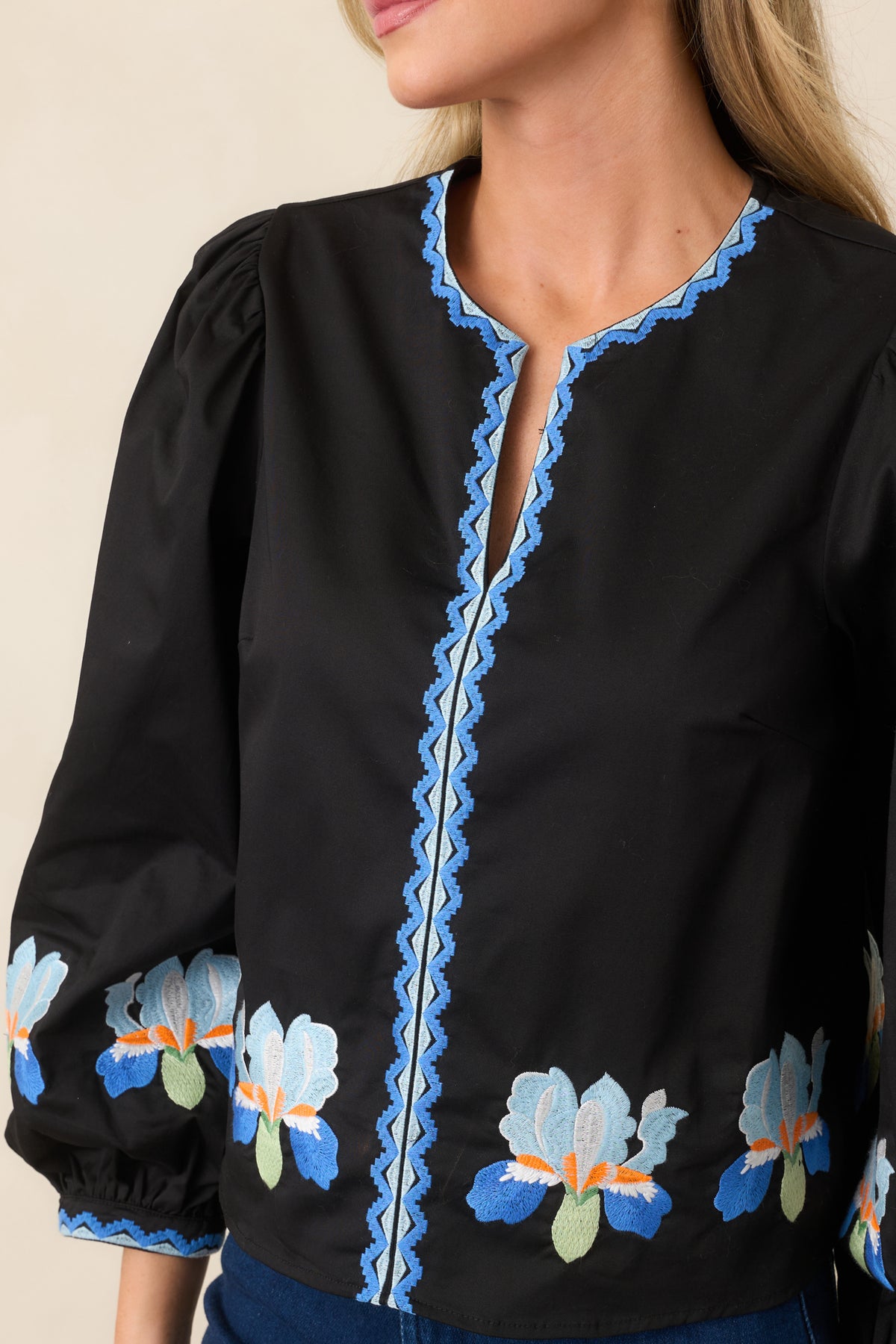 Close-up of blue iris and geometric embroidery around the neckline.