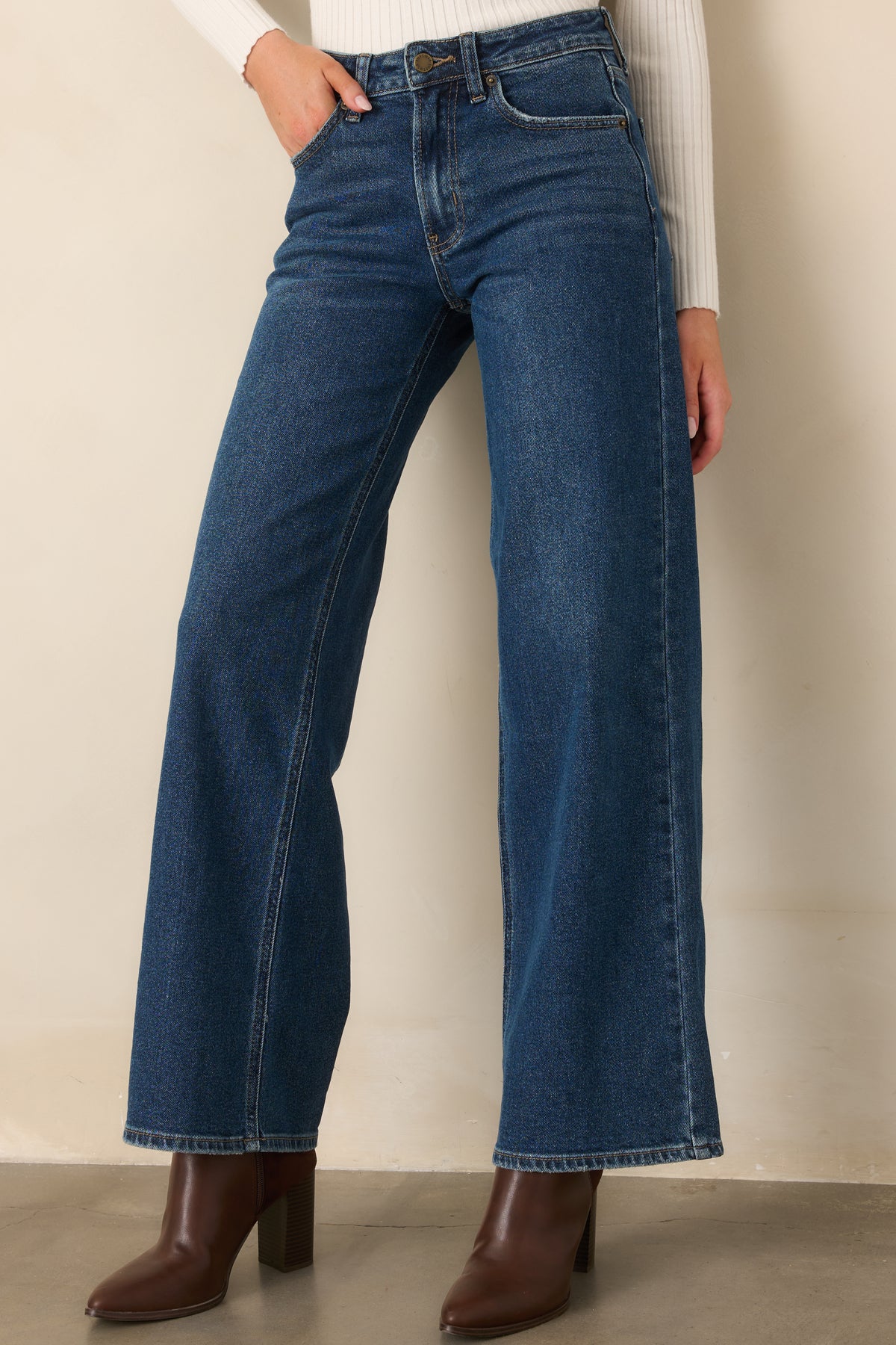 Rich blue denim jeans highlight the high-rise waistband, belt loops, and button-front closure.