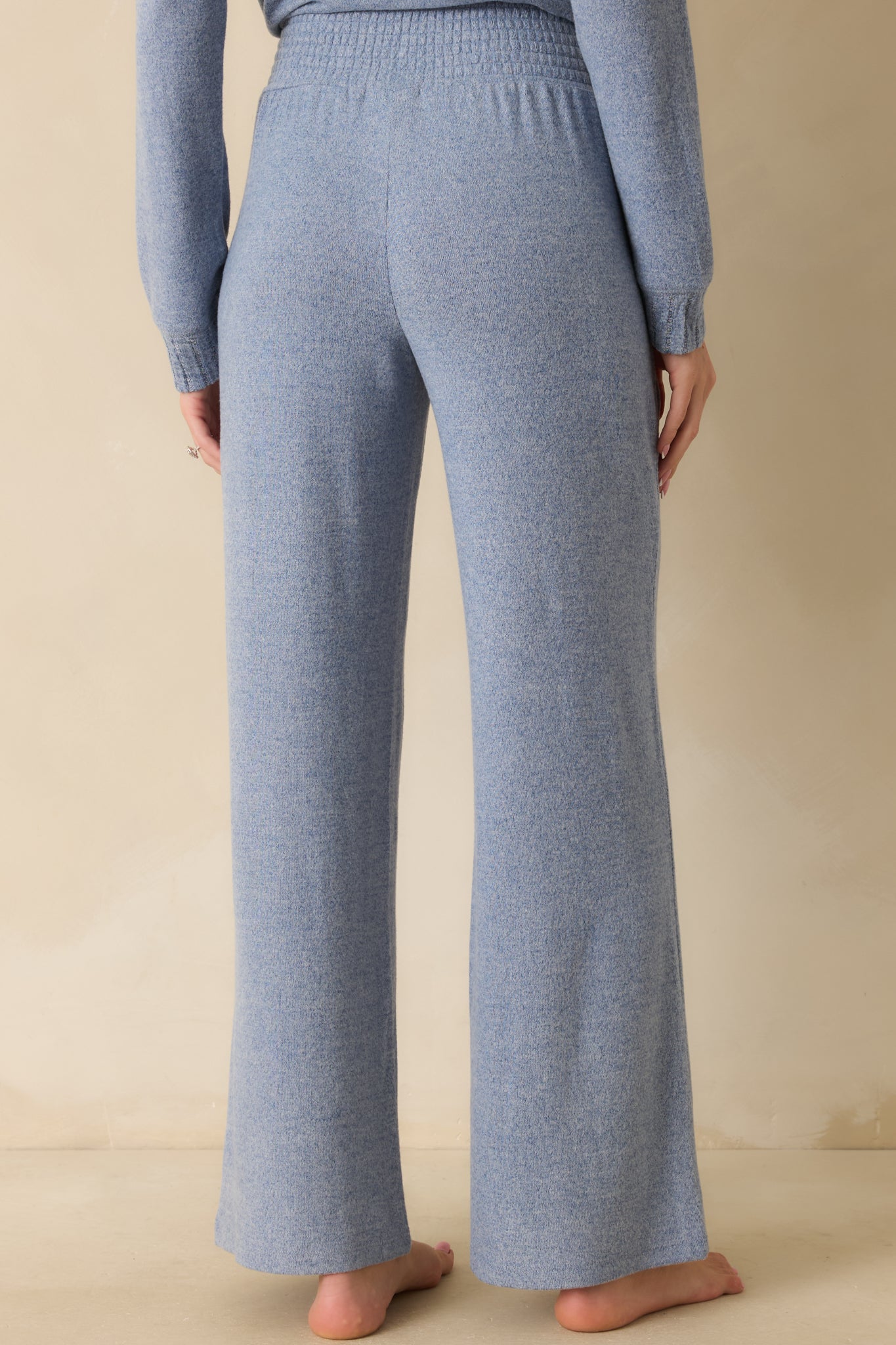 Rear view of high-rise blue knit pants showing wide-leg silhouette and smooth knit finish.