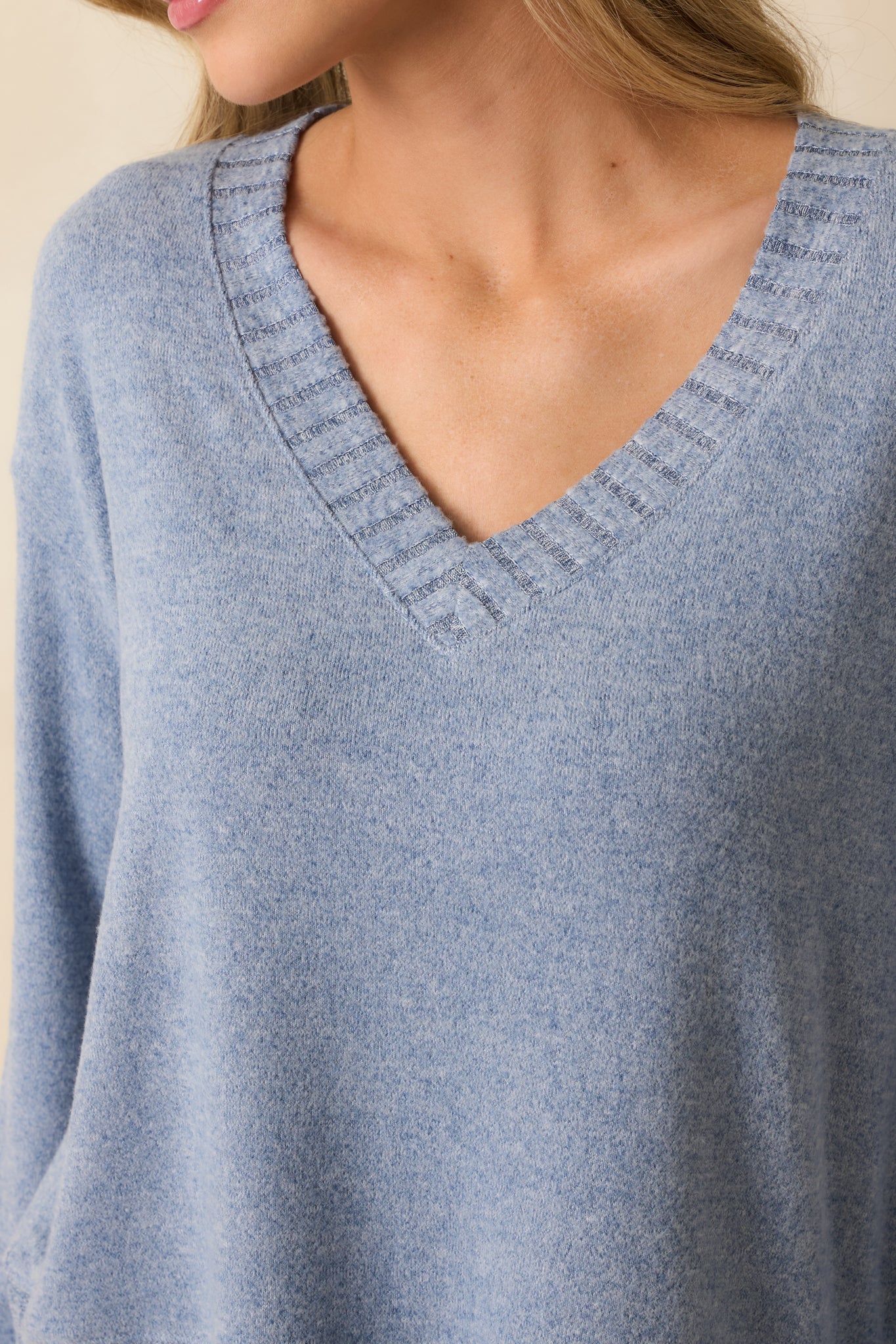 Tight view of plush blue knit fabric and ribbed V-neckline for a luxurious texture focus.