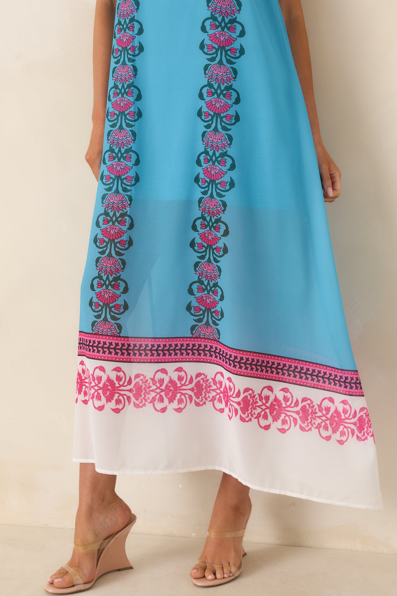 Close-up of the blue maxi dress hem featuring bold floral border prints, contrasting panels, and lightweight fabric with an elegant drape.