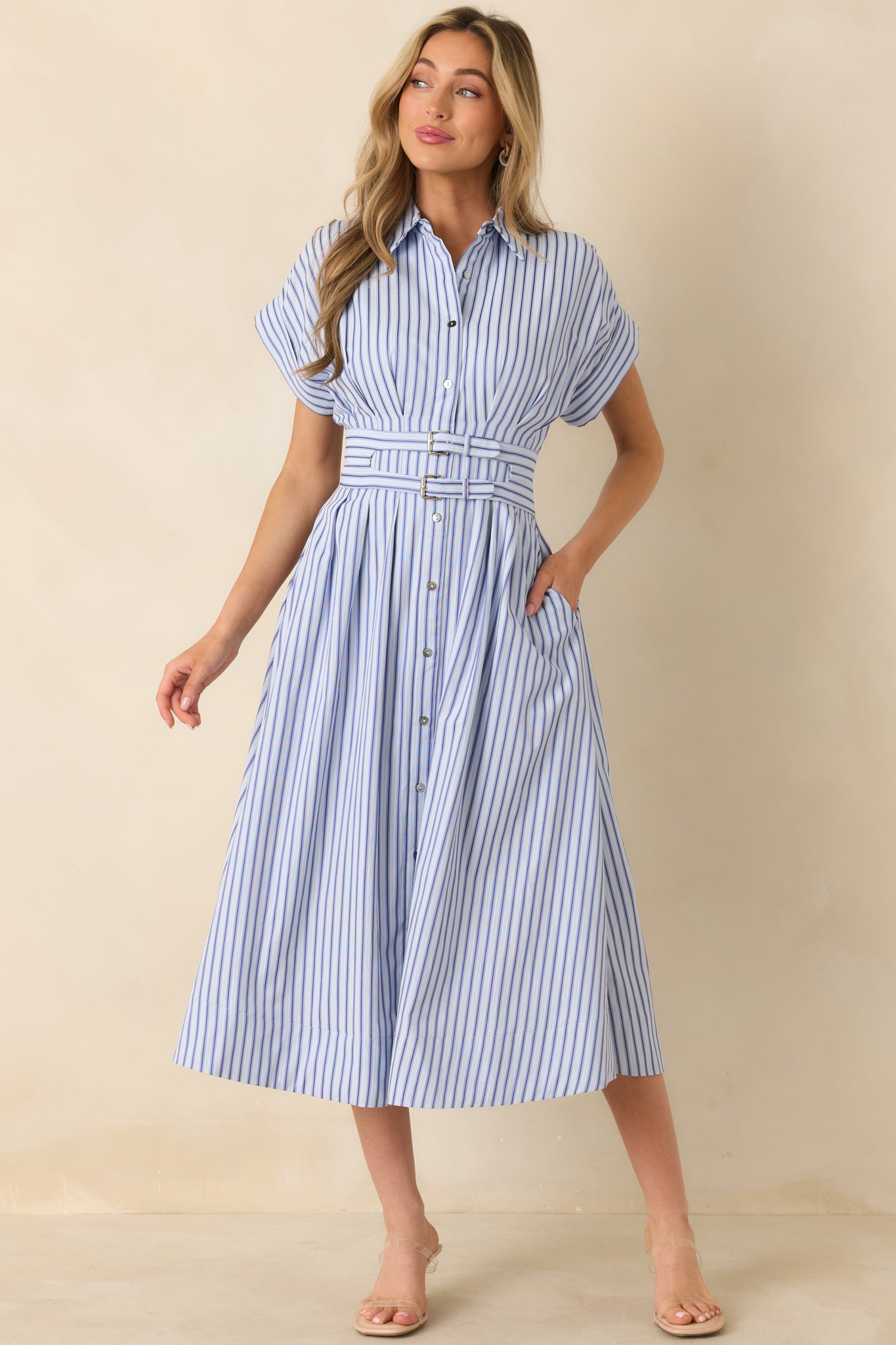Blue vertically striped midi dress designed with a collared button-down bodice and soft pleats flowing through the skirt.
