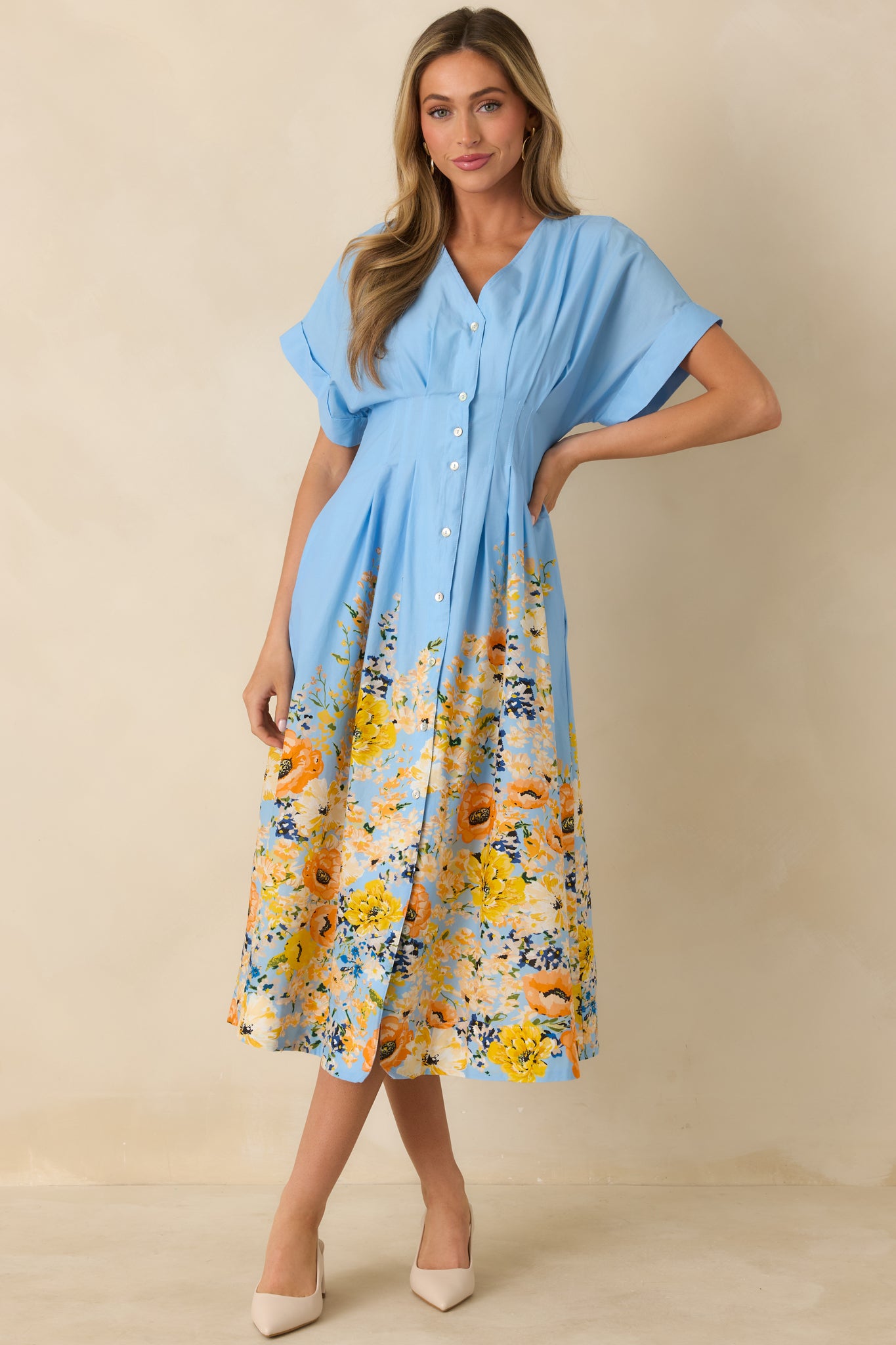 Blue cotton midi dress with V-neckline, flutter sleeves, and button-down front, showing flowy skirt and defined waist.