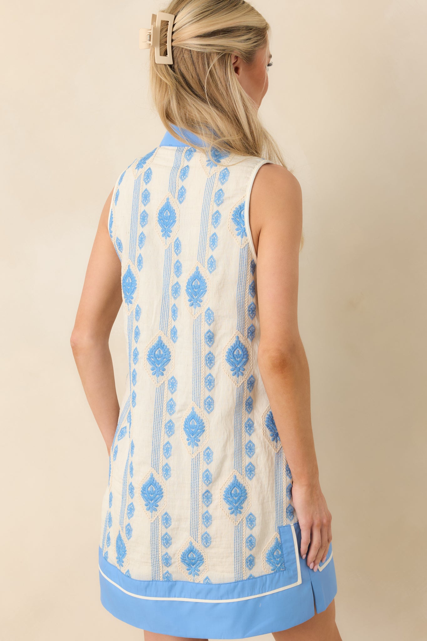 Blue sleeveless mini shift dress displaying a smooth rear silhouette with straight cut and subtle side slit.