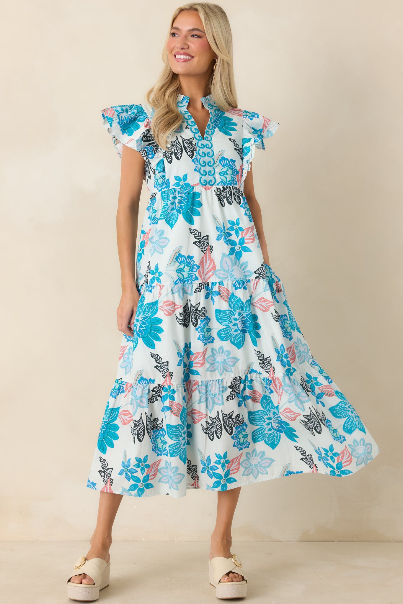 Blue multi midi dress highlighting vibrant floral patterns, side pockets, flutter sleeves, and a flowing shape.